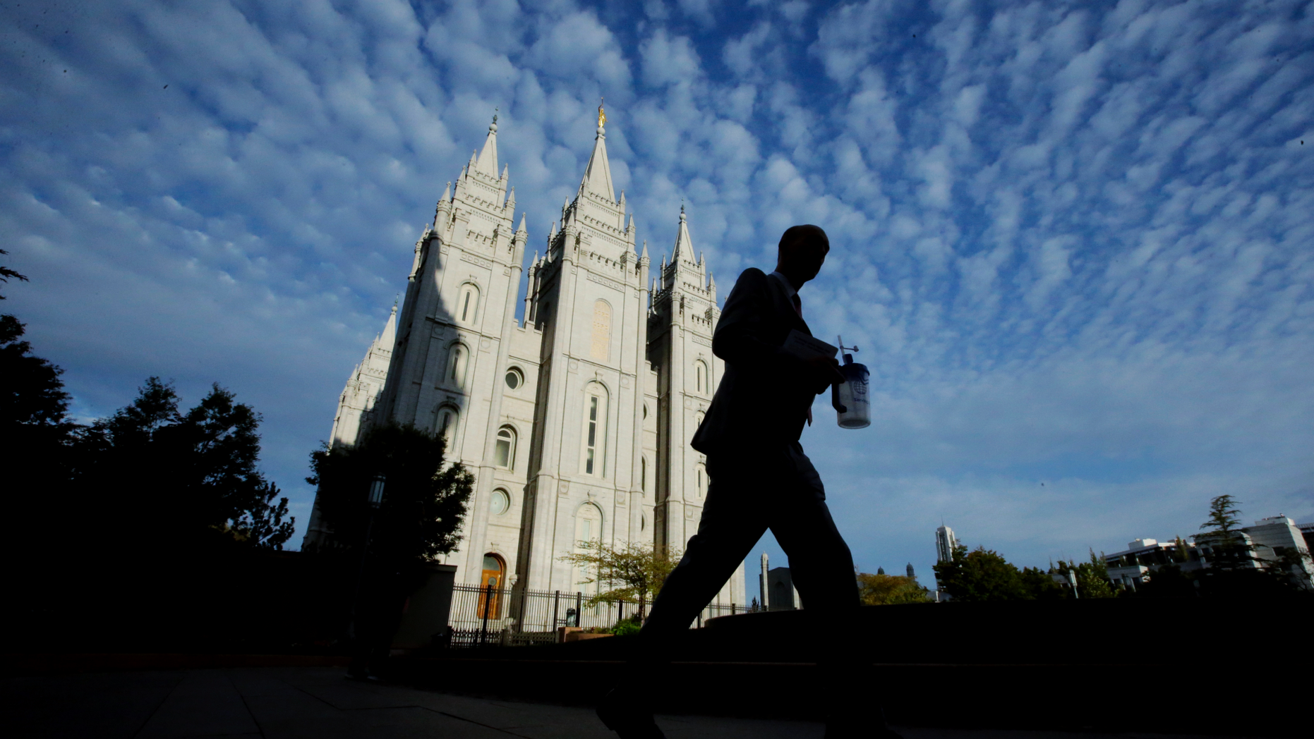 FILE - In this Sept. 14, 2016, file photo, a man walks past the Salt Lake Temple, a temple of The Church of Jesus Christ of Latter-day Saints, at Temple Square in Salt Lake City. Parents of Mormon missionaries will be able to hear their children's voices a lot more often under new rules announced Friday, Feb. 15, 2019, that allow the proselytizing youngsters to call home every week instead of only twice a year. (AP Photo/Rick Bowmer, File)