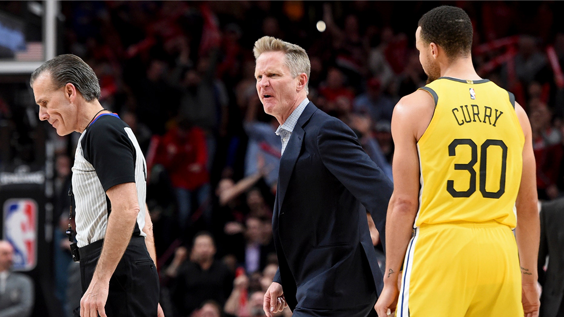Golden State Warriors coach Steve Kerr, center, yells at referee Ken Mauer, left, after being called for a technical foul, while guard Stephen Curry, right, watches during the second half of an NBA basketball game against the Portland Trail Blazers in Portland, Ore., Wednesday, Feb. 13, 2019. The Blazers won 129-107.