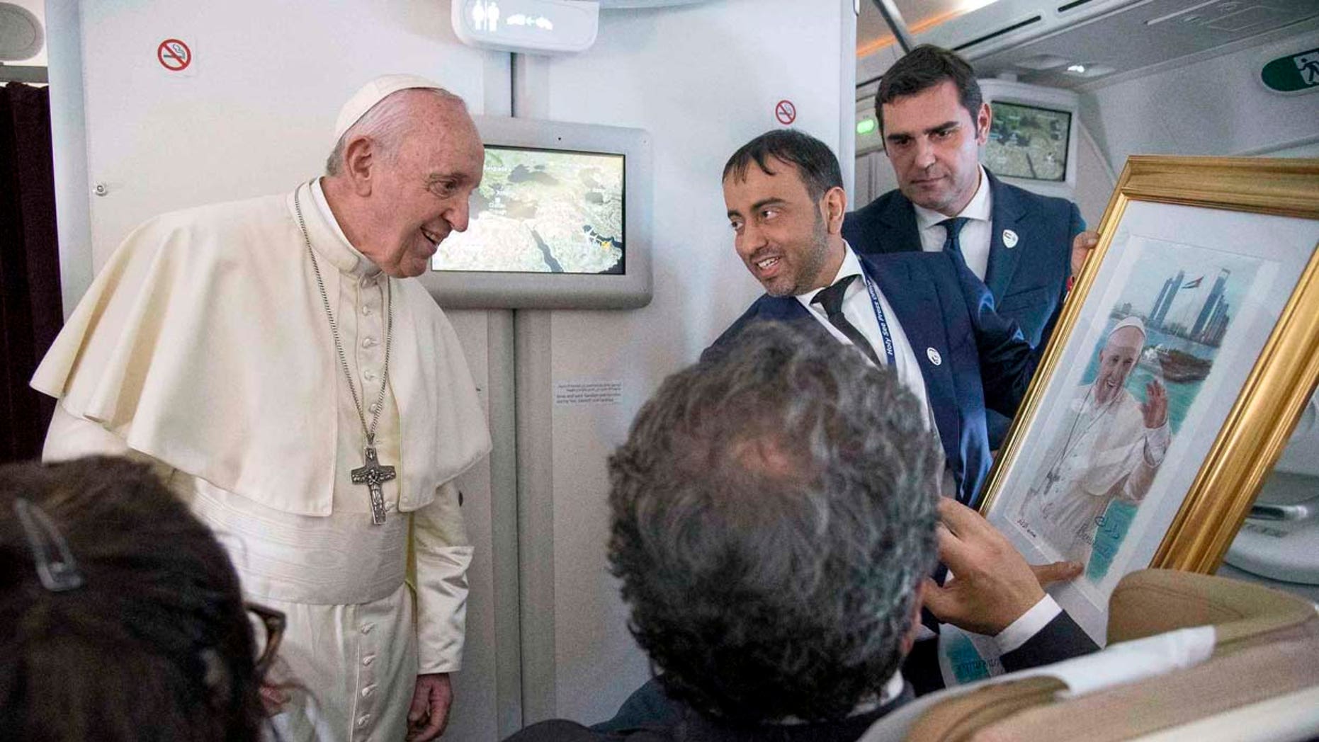 Pope Francis receives a gift from a journalist during his flight from Abu Dhabi to Rome, Tuesday, Feb. 5, 2019. Pope Francis has concluded his historic visit to the Arabian Peninsula with the first-ever papal Mass in the birthplace of Islam. (Luca Zennaro/Pool Photo via AP)