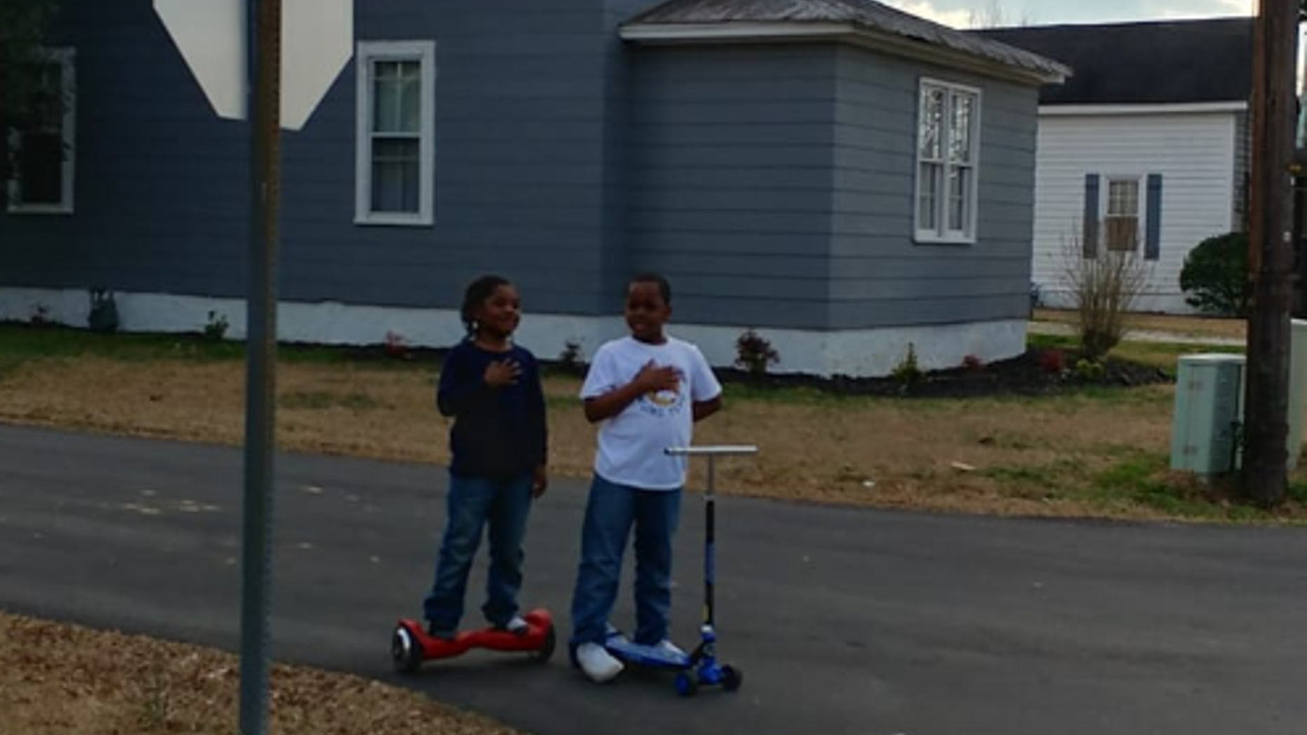 Two boys reciting the pledge of allegiance in front of a North Carolina fire station.