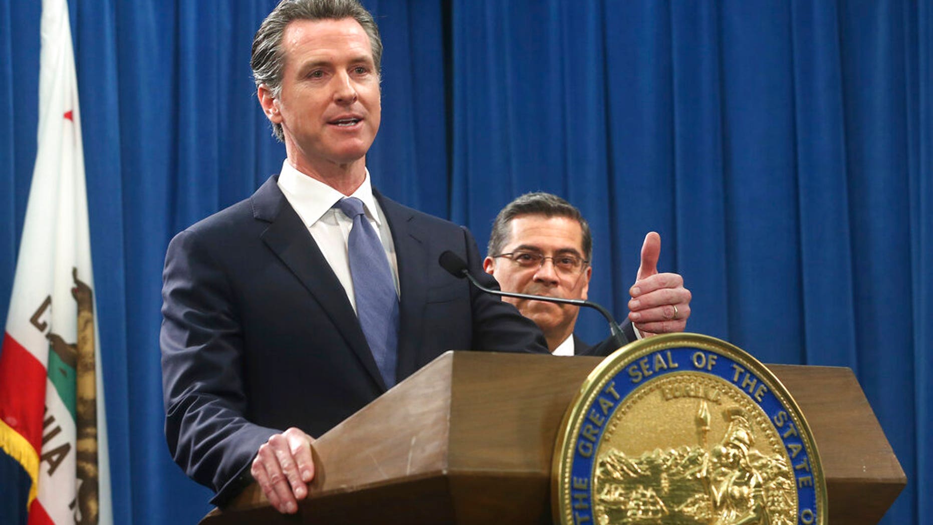 California Gov. Gavin Newsom, left, flanked by Attorney General Xavier Becerra, right, answers a question concerning a lawsuit the state will likely file against President Donald Trump over his emergency declaration to fund a wall on the U.S.-Mexico border Friday, Feb. 15, 2019, in Sacramento, Calif. Newsom and Becerra both say there is no emergency at the border and Trump doesn't have the authority to make the declaration. (AP Photo/Rich Pedroncelli)