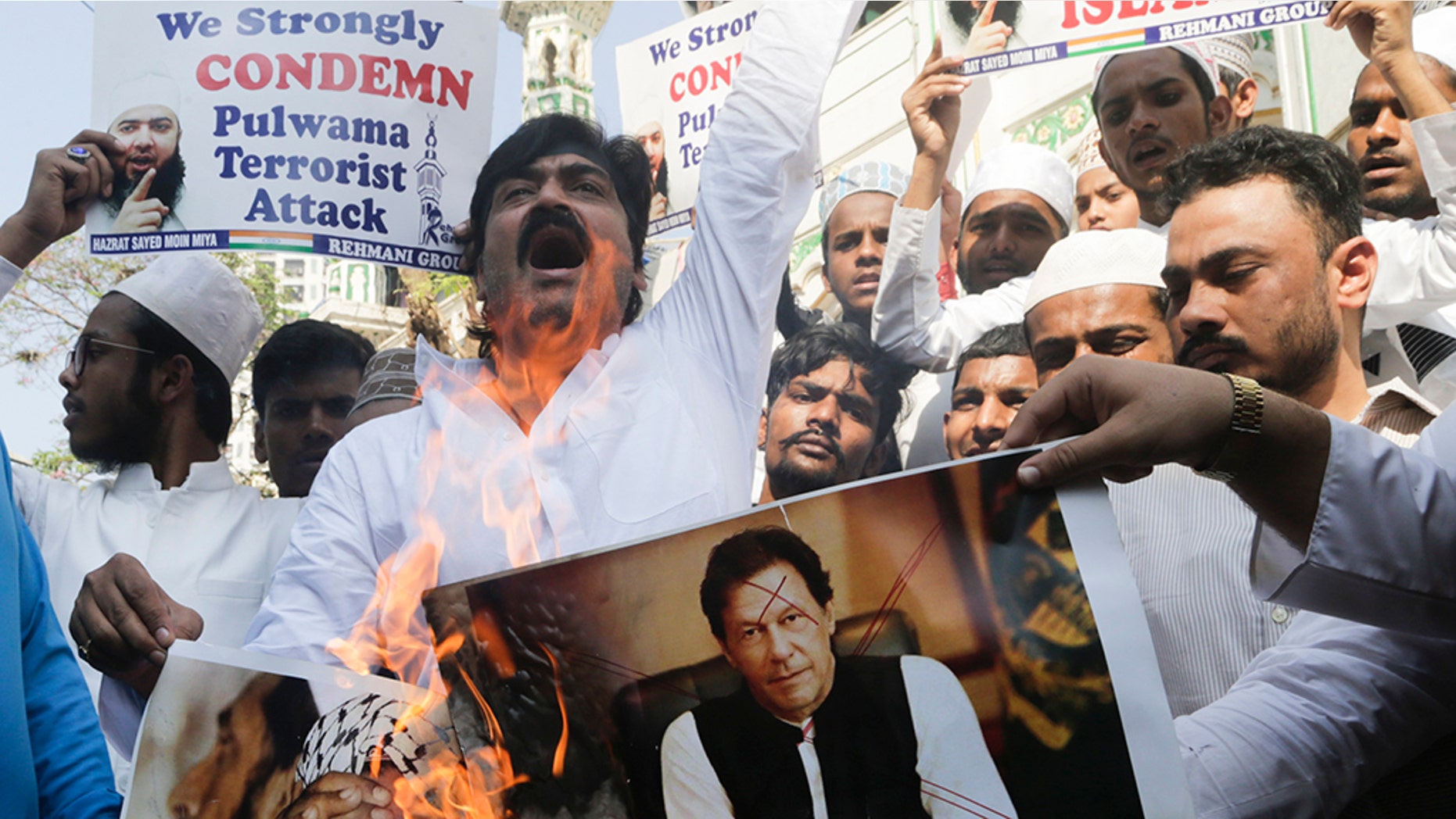 Indian Muslims burn posters of Pakistani prime minister Imran Khan, center, and Jaish-e-Mohammed leader Masood Azhar, during a protest against Thursday's attack on a paramilitary convoy in Kashmir that killed at least 40, in Mumbai, India, Friday.