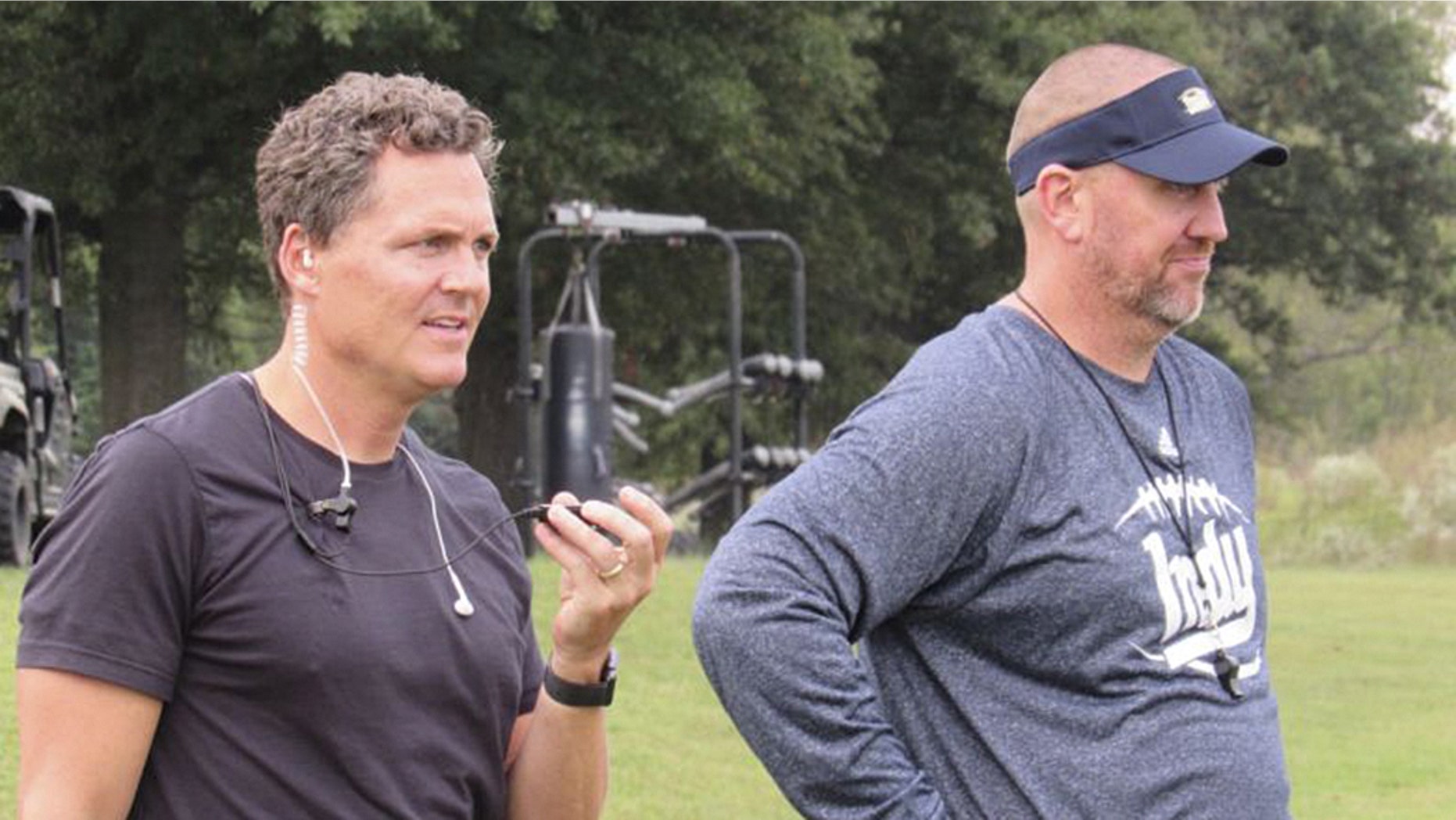 Director Greg Whiteley, left, and Independence Community College football coach Jason Brown, watch a practice during a shoot for the Netflix series "Last Chance U." in Independence, Kan. The series exposes the grim and gritty world of high-stakes junior-college football.