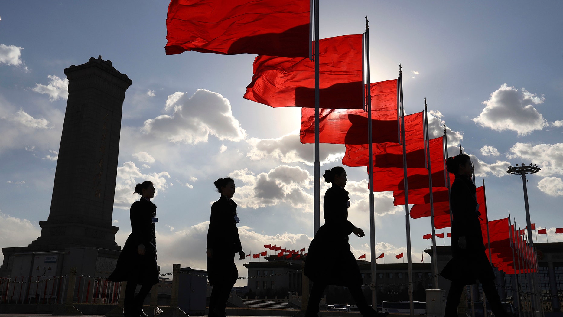 Bus ushers walk past red flags on Tiananmen Square during a plenary session of the Chinese People's Political Consultative Conference (CPPCC) at the Great Hall of the People in Beijing Monday, March 11, 2019 - file photo.