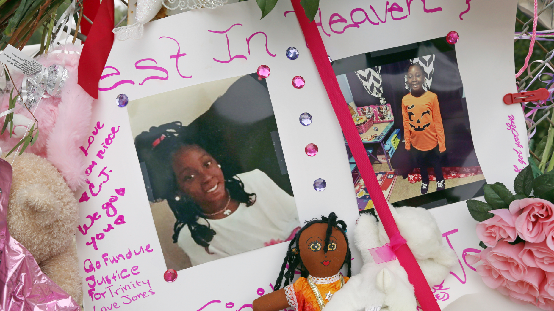 Photos adorn a large memorial to Trinity Love Jones, the 9-year-old girl whose body was found in a duffel bag along a suburban Los Angeles equestrian trail, in Hacienda Heights, Calif., Monday, March 11, 2019. Two people have been detained in connection with the case. The discovery happened last week. (AP Photo/Reed Saxon)