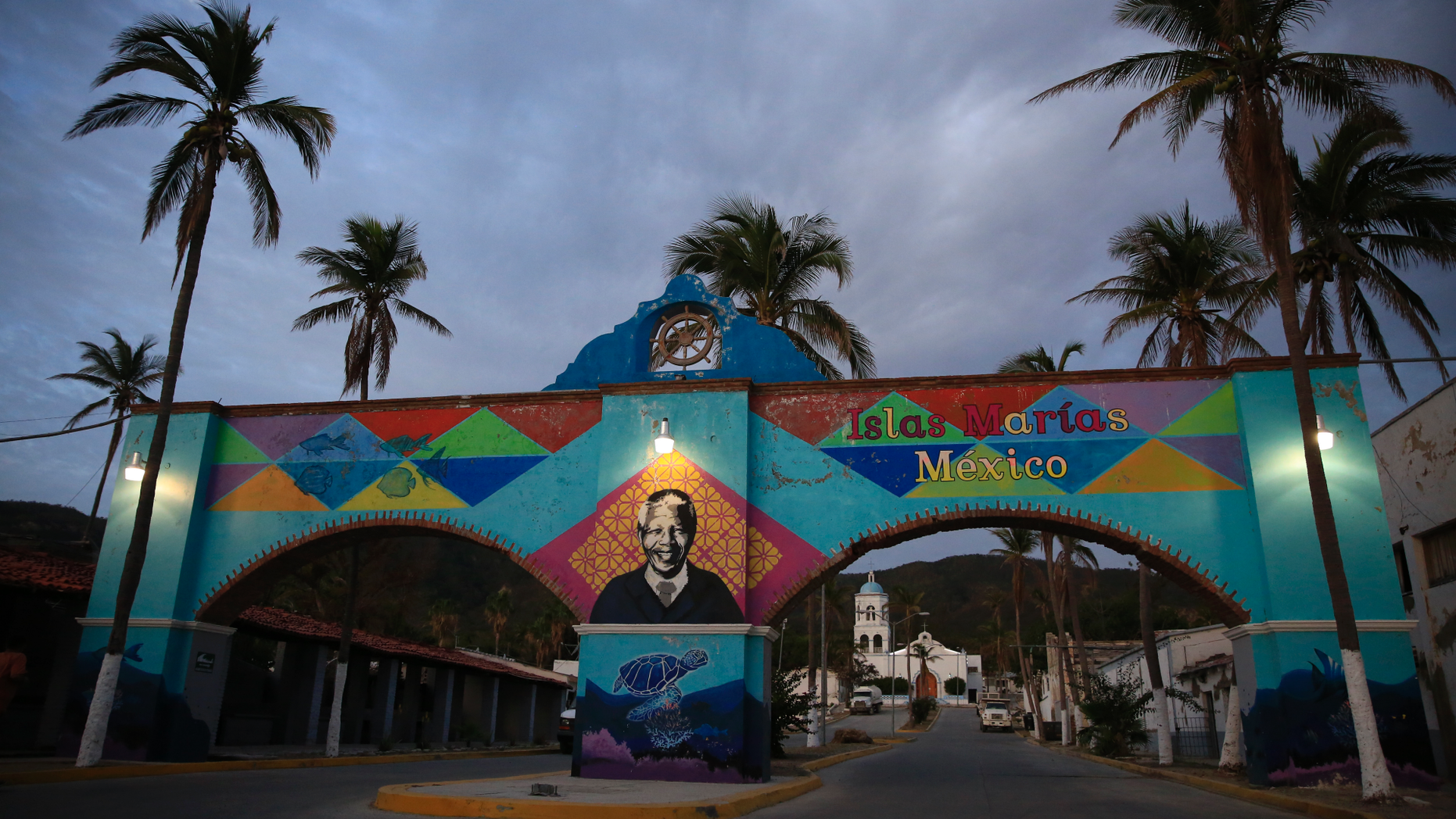 A mural of Nelson Mandela, who spent many of his imprisoned years in an island prison in South Africa, adorns a gate in front of the dock where prison staff and inmates arrive in Navy boats to the now closed Islas Maria penal colony located off Mexico's Pacific coast, at dawn Sunday, March 17, 2019. Islas Marias was the last of its kind, the final of a half dozen island penal colonies that were scattered around Latin America. (AP Photo/Rebecca Blackwell)