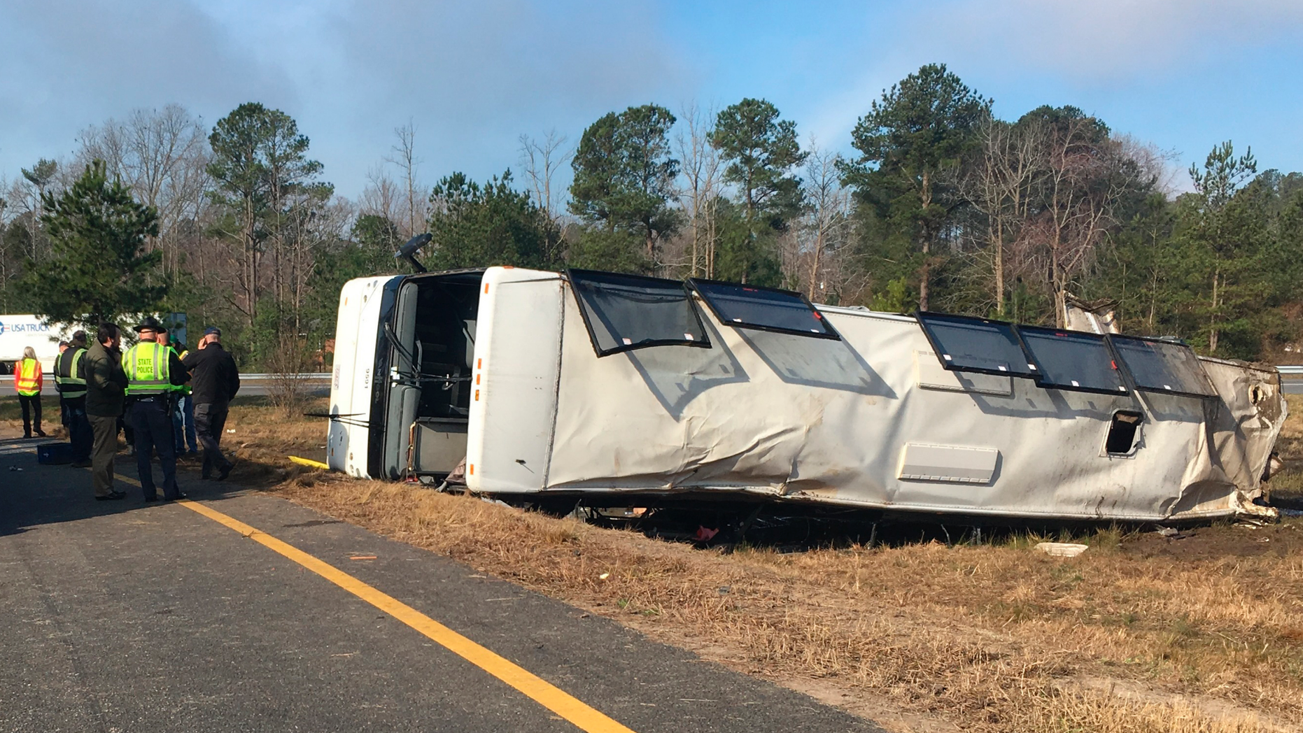 This photo provided by Virginia State Police emergency responders at the scene after a charter bus overturned on an Interstate 95 exit near Kingwood, Va., Tuesday, March 19, 2019. Virginia State Police say in a statement that the Tao's Travel Inc. bus with 57 people aboard overturned on an Interstate 95 exit Tuesday in Prince George County. Police say that as the bus turned onto the exit, it ran off the left side and overturned. (Virginia State Police via AP)