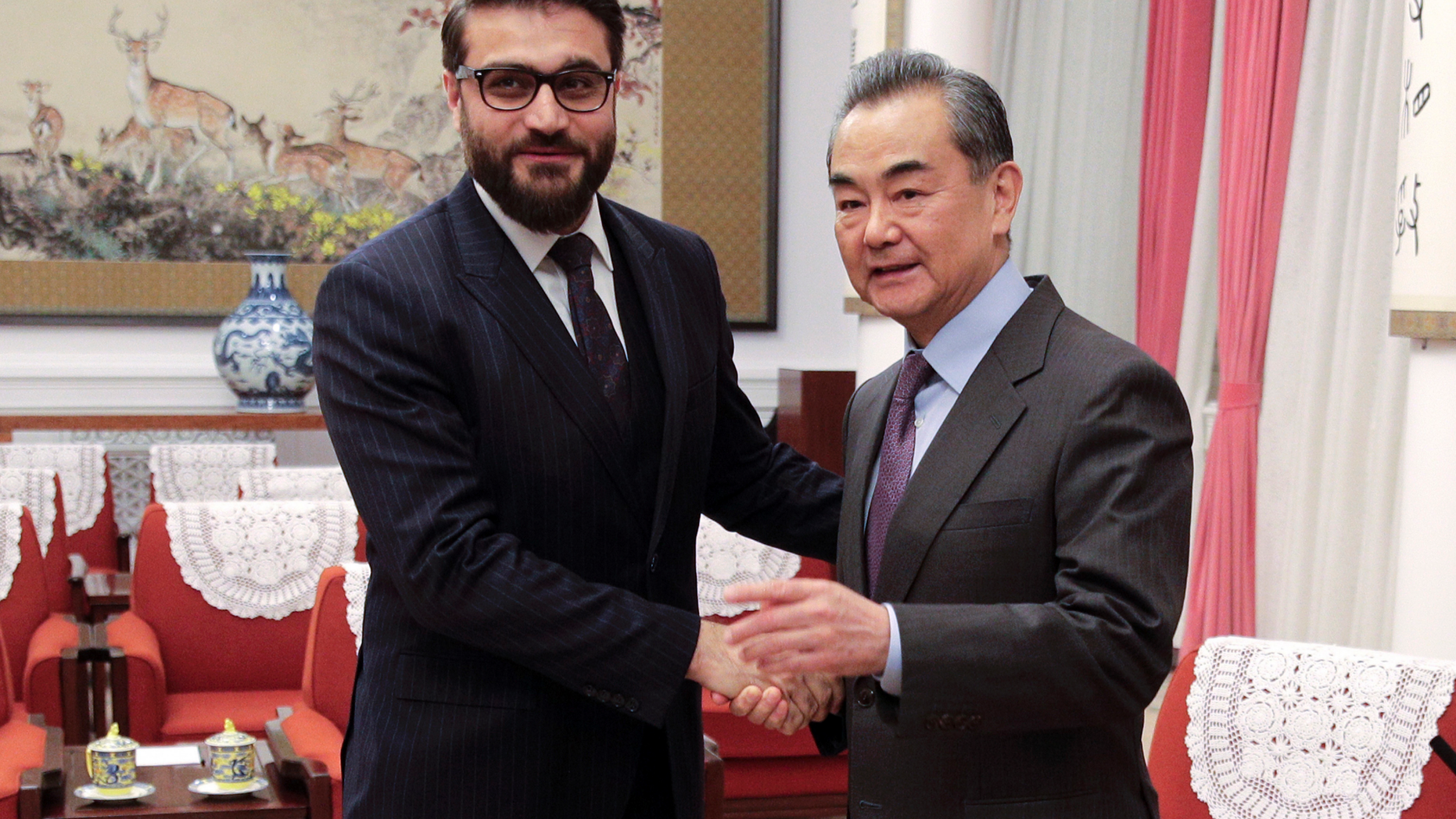 FILE - In this Jan. 10, 2019, file photo, Afghanistan national security adviser Hamdullah Mohib, left, shakes hands with Chinese Foreign Minister Wang Yi before proceeding to their meeting at the Zhongnanhai Leadership Compound in Beijing. Hamdullah Mohib is blasting U.S. talks with the Taliban, saying the Trump administration has alienated the Afghan government, legitimized the militant network and is crafting a deal that will never lead to peace. (AP Photo/Andy Wong, Pool)