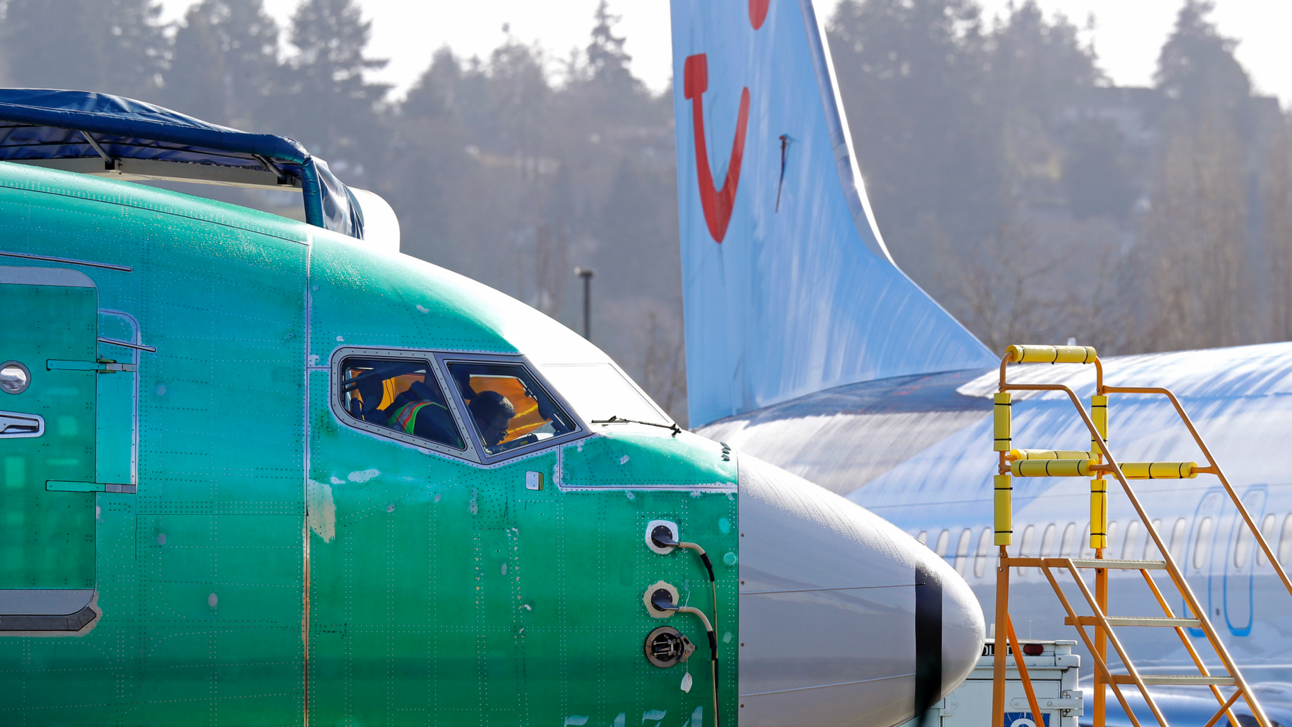FILE- In this March 13, 2019, file photo people work in the flight deck of a Boeing 737 MAX 8 airplane being built for TUI Group parked next to another MAX 8 also designated for TUI at Boeing Co.'s Renton Assembly Plant in Renton, Wash. U.S. prosecutors are looking into the development of Boeing's 737 Max jets, a person briefed on the matter revealed Monday, the same day French aviation investigators concluded there were "clear similarities" in the crash of an Ethiopian Airlines Max 8 last week and a Lion Air jet in October. (AP Photo/Ted S. Warren, file)