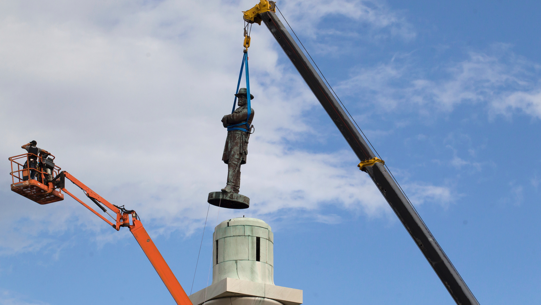 FILE- In this May 19, 2017 file photo, a statue of Confederate General Robert E. Lee is removed from Lee Circle in New Orleans. The statues of Confederate President Jefferson Davis and generals Robert E. Lee and P.G.T. Beauregard remain in a city warehouse where they were stored after their removal in the spring of 2017. (AP Photo/Scott Threlkeld, File)
