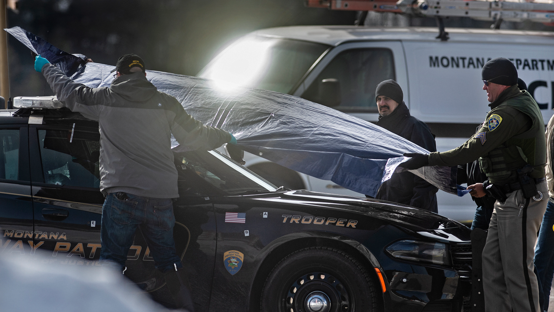 Police forces cover the car of Montana State Wade Palmer on the scene of the shooting near Evaro Bar on Friday, March 15, 2019, in Missoula, Mt. Palmer, who was investigating a previous shooting, was himself shot and wounded last Friday after he discovered the suspect's vehicle, prompting authorities to launch a manhunt that would have resulted in the shooting. arrest of a 29-year-old man, officials said. (Tommy Martino / The Missoulian via AP)