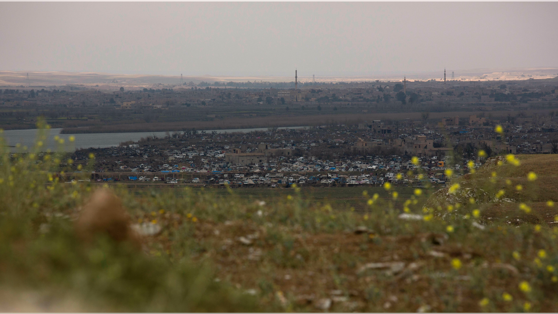 In this Sunday, March 17, 2019, photo, the Islamic State group's last pocket of territory in Baghouz, Syria, as seen from a distance. On Tuesday, a spokesman for U.S.-backed forces fighting IS in Syria says his fighters are in control of an encampment in the village of Baghouz where IS militants have been besieged for months. (AP Photo/Maya Alleruzzo)