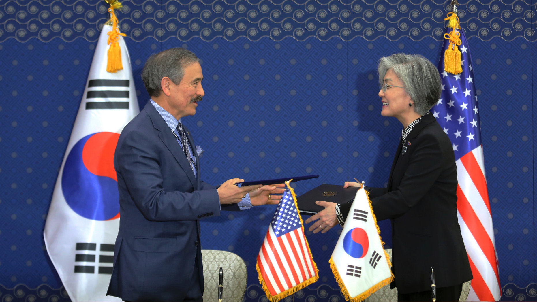 South Korean Foreign Minister Kang Kyung-wha, right, and U.S. Ambassador to South Korea Harry Harris exchange documents at Foreign Ministry in Seoul, South Korea, Friday, March 8, 2019. South Korea and the United States have formally signed a deal that increases Seoul's financial contribution for the deployment of U.S. troops in the Asian country. (AP Photo/Ahn Young-joon, Pool)