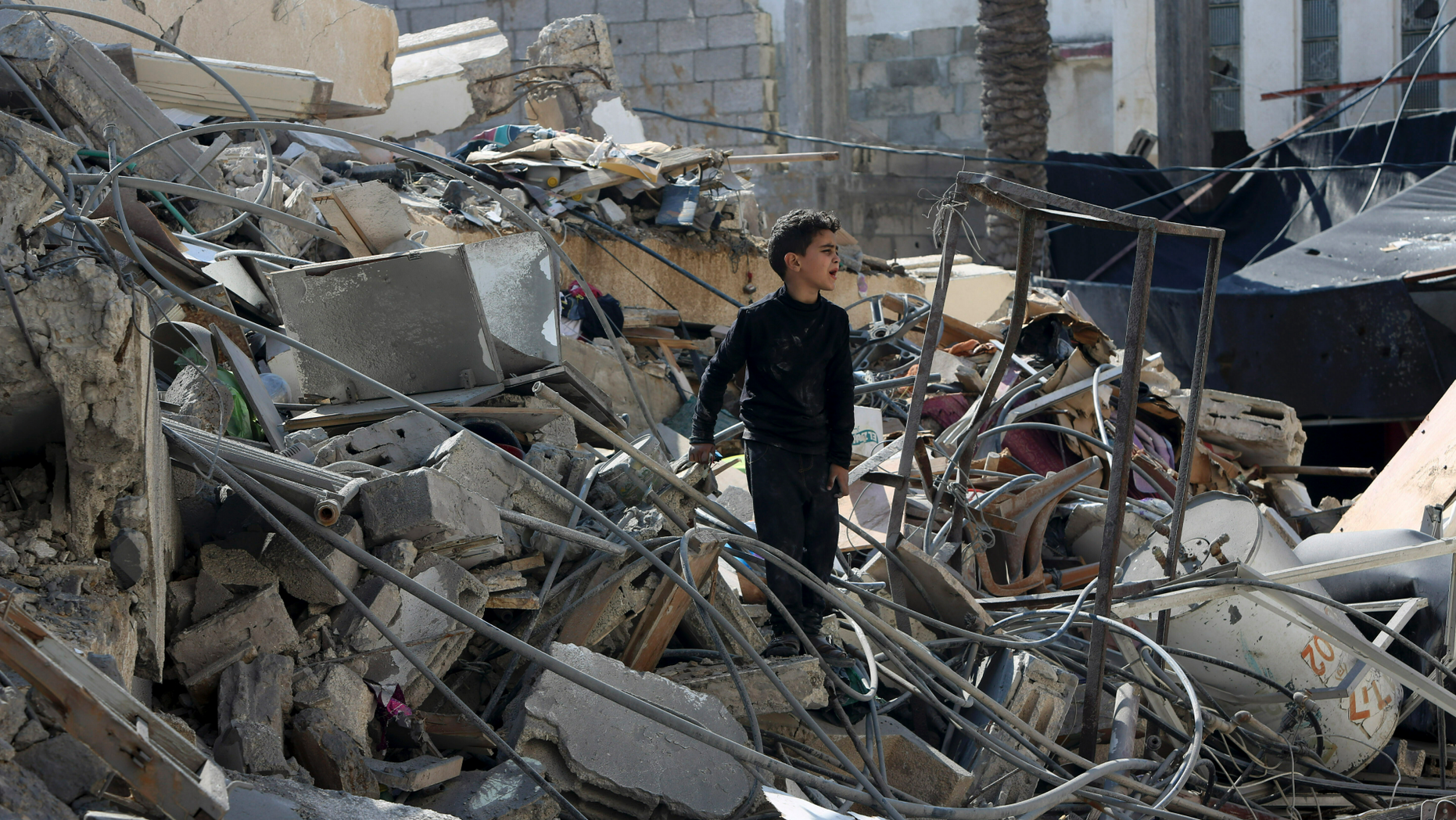 A Palestinian boy searches for their family's belongings amid the rubble of a destroyed building near a Hamas security building that was destroyed in an Israeli airstrike late Monday, in Gaza City, Wednesday, March 27, 2019. (AP Photo/Adel Hana)