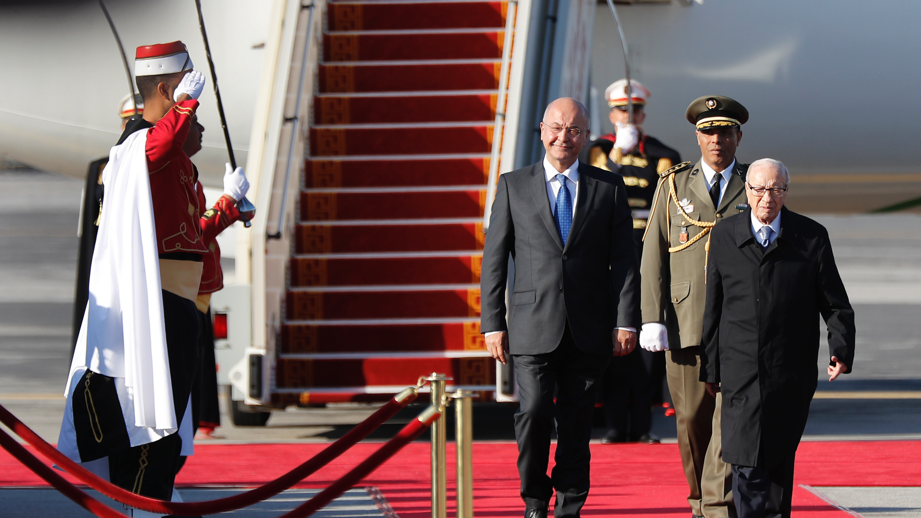 Iraq's President Barham Salih, left, walks next of his Tunisian counterpart Beji Caid Essebsi, right, as they review the honor guard upon his arrival at Tunis-Carthage international airport to attend the Arab Summit, in Tunis, Tunisia, Saturday, March 30, 2019. (AP Photo/Hussein Malla, Pool)