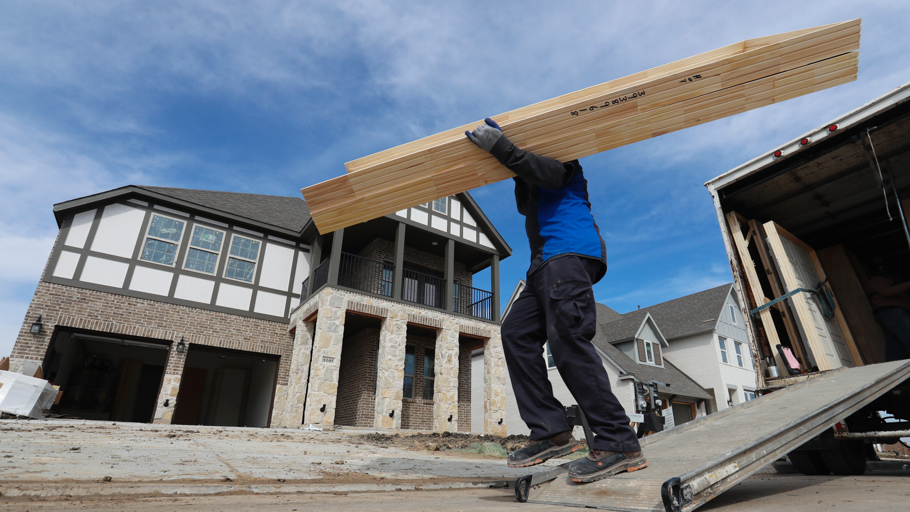 FILE- In this Feb. 20, 2019, file photo a worker carries interior doors to install in a just completed new home in north Dallas. On Tuesday, March 26, the Commerce Department reports on U.S. home construction in February. (AP Photo/LM Otero, File)