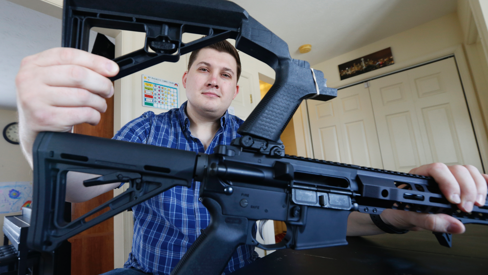 In this March 15, 2019 photo, Ryan Liskey displays a bump stock on top of his AR-15 at his home in Harrisonburg, Va. The ban on bump stocks is just a few days away and owners of the devices like Liskey are trying to figure out what to do. (AP Photo/Steve Helber)