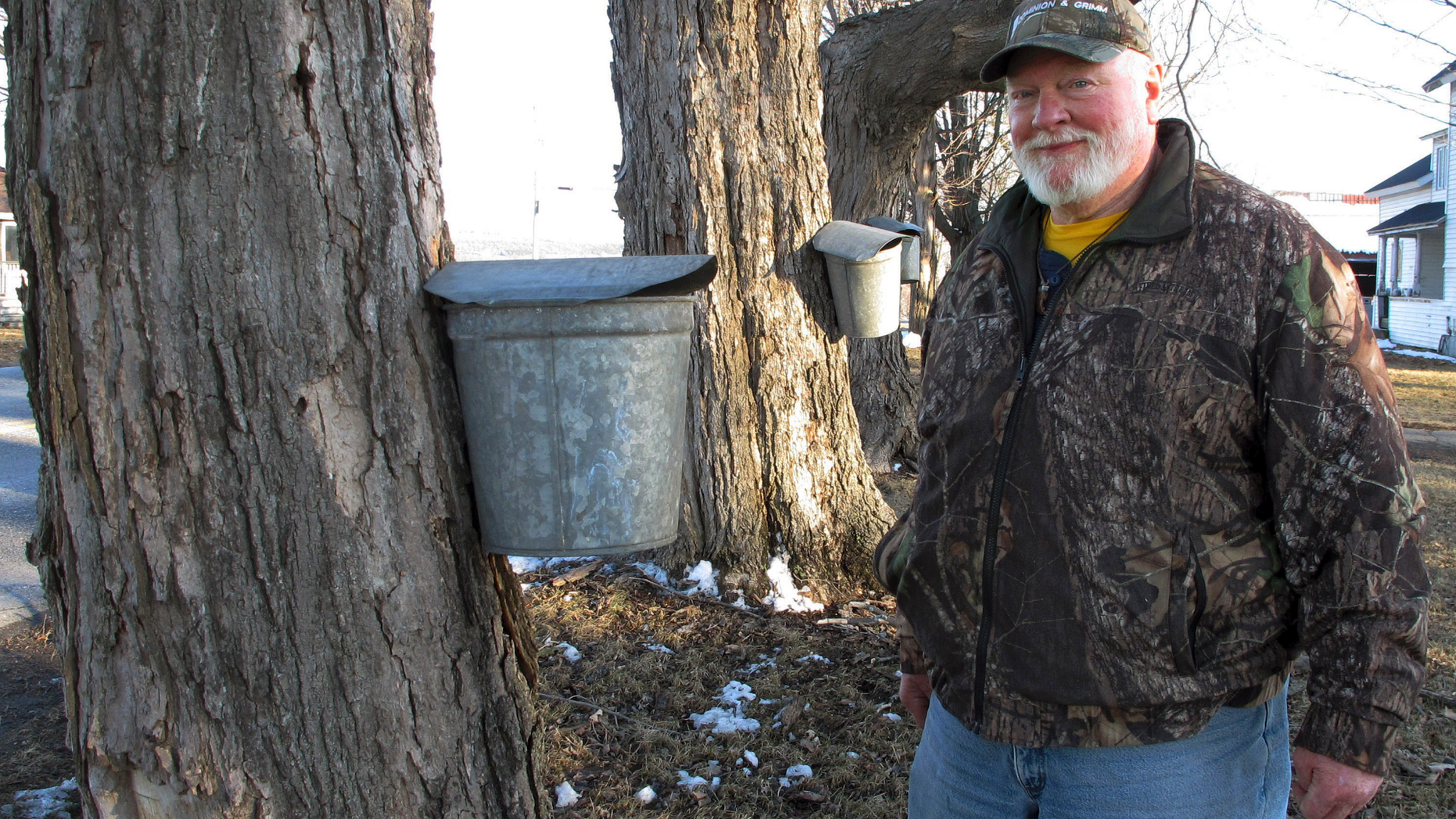 In this Wednesday, March 27, 2019 photo, maple syrup maker Fred Hopkins stands next to sap-collecting buckets in St. Albans, Vt., lent to him after 140 of his buckets were stolen off trees. (AP Photo/Lisa Rathke)