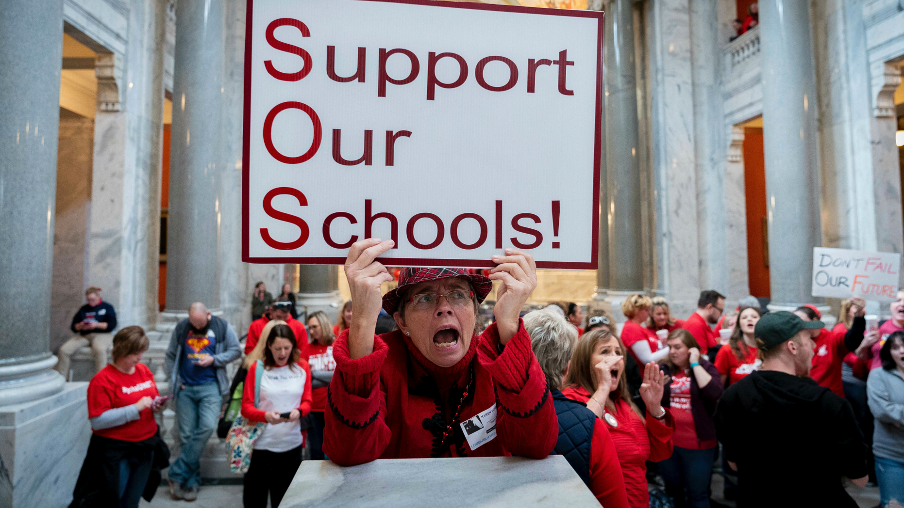 Karen Schwartz, a teacher at the Phoenix School of Discovery in Louisville, stands alongside other teachers and their supporters to protest the attacks on public education in Frankfort, Ky on Tuesday, March 12, 2019 (AP Photo / Bryan Woolston)