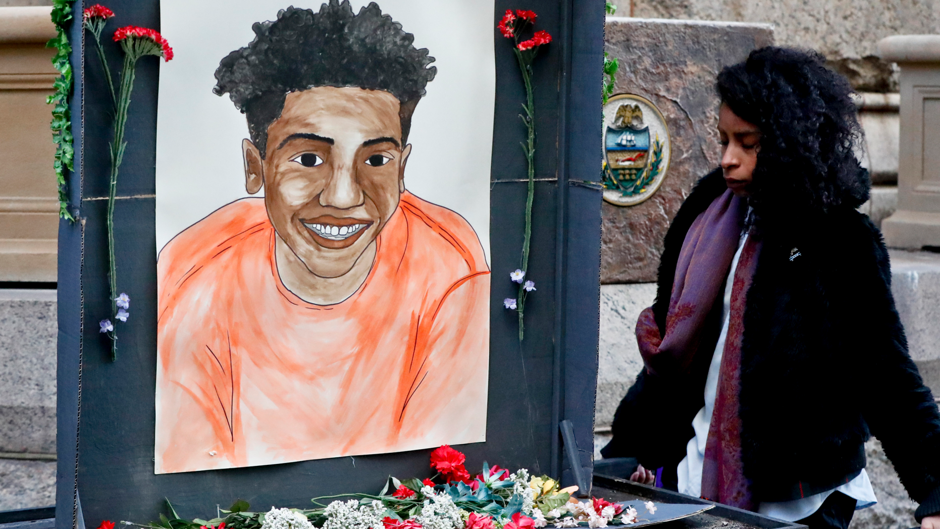 A woman who did not want to be identified holds a memorial display with a drawing of Antwon Rose II in front of the court house on the first day of the trial for Michael Rosfeld, a former police officer in East Pittsburgh, Pa., begins on Tuesday, March 19, 2019, in Pittsburgh. Rosfeld is charged with criminal homicide in the fatal shooting of Antwon Rose II as he fled during a traffic stop on June 19, 2018. (AP Photo/Keith Srakocic)