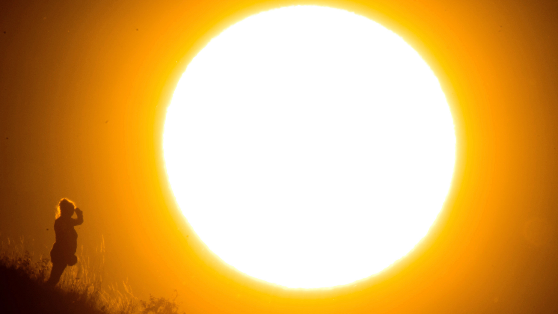 File-- Photo taken July 2, 2018 shows a stroller pausing in front of the setting sun at Kronsberg mountain in Hannover, Germany. (Julian Stratenschulte/dpa via AP)