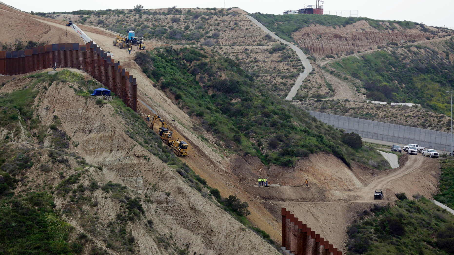 Construction crews replace a section of the primary wall separating San Diego, above right, and Tijuana, Mexico, below left, Monday, March 11, 2019, seen from Tijuana, Mexico. President Donald Trump is reviving his border wall fight, preparing a new budget that will seek $8.6 billion for the U.S-Mexico barrier while imposing steep spending cuts to other domestic programs and setting the stage for another fiscal battle. (AP Photo/Gregory Bull)