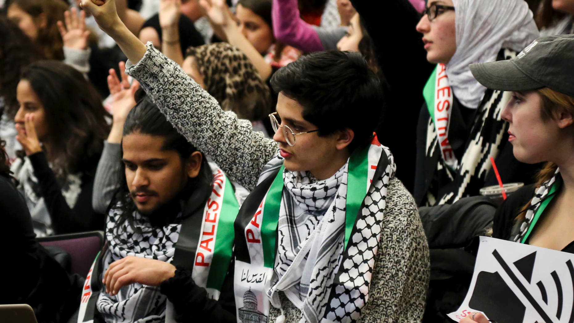 FILE - In this Tuesday, Nov. 14, 2017 file photo, a student holds up their fist in support of a speaker during a University of Michigan Student Government meeting in Ann Arbor, Mich., to vote on a resolution to divest in businesses connected to Israel amid criticism of Israeli policies toward Palestinians. On college campuses, in state legislatures and in many other venues nationwide, the polarized debate about Israel is a familiar conflict and likely to intensify. (Hunter Dyke/The Ann Arbor News via AP)