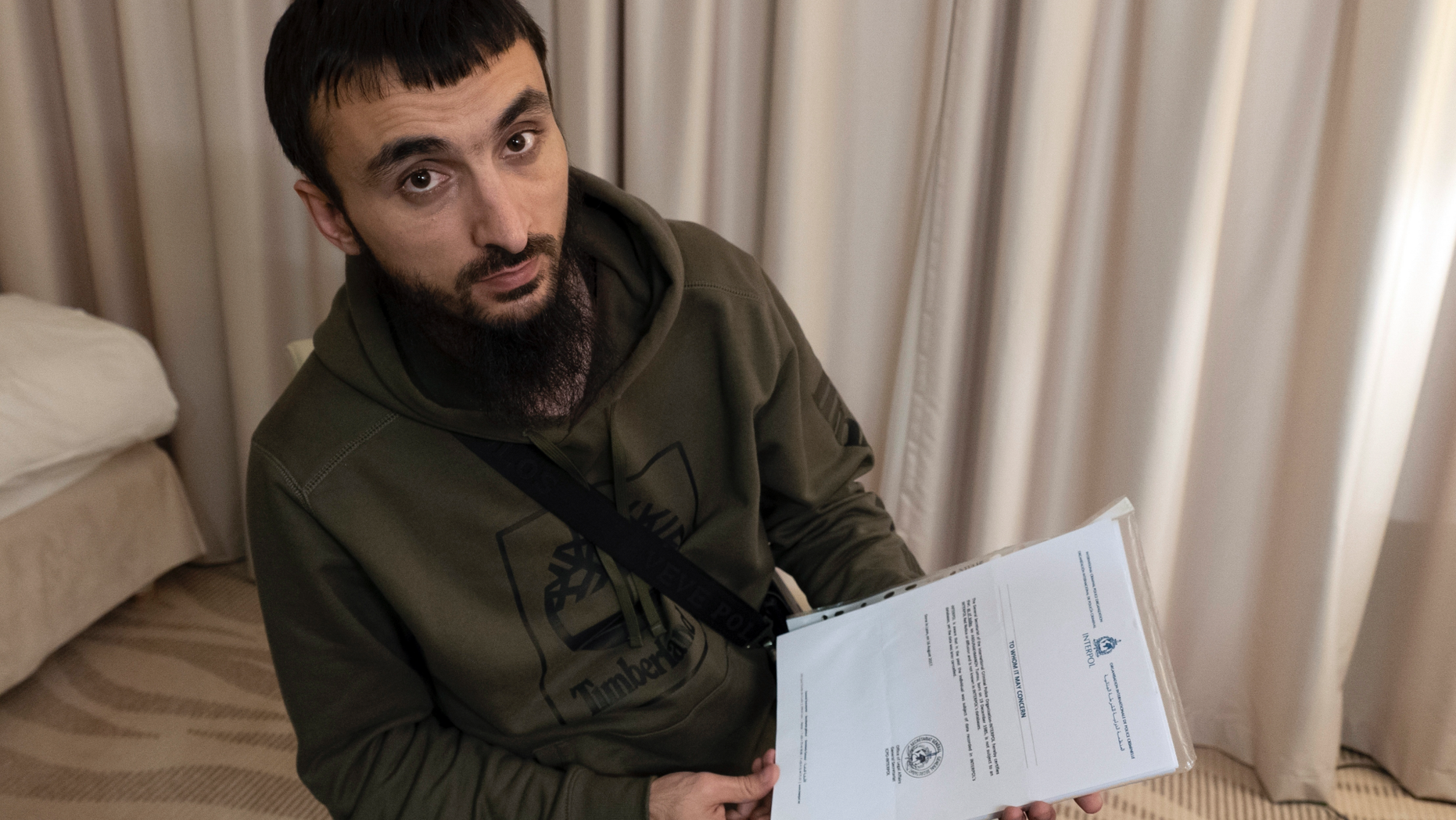 FILE - In this file photo taken on Wednesday, Nov. 14, 2018, Tumso Abdurakhmanov, the 32-year-old Chechen video blogger, and critic of the Chechen ruler Ramzan Kadyrov, holds a letter from Interpol during an interview with The Associated Press somewhere in Poland. The speaker of Chechnya's parliament Magomedov Daudov, says he has a blood feud against the popular Chechen blogger who has fled Russia and is believed to be seeking asylum in Poland. (AP Photo/Francesca Ebel, File)