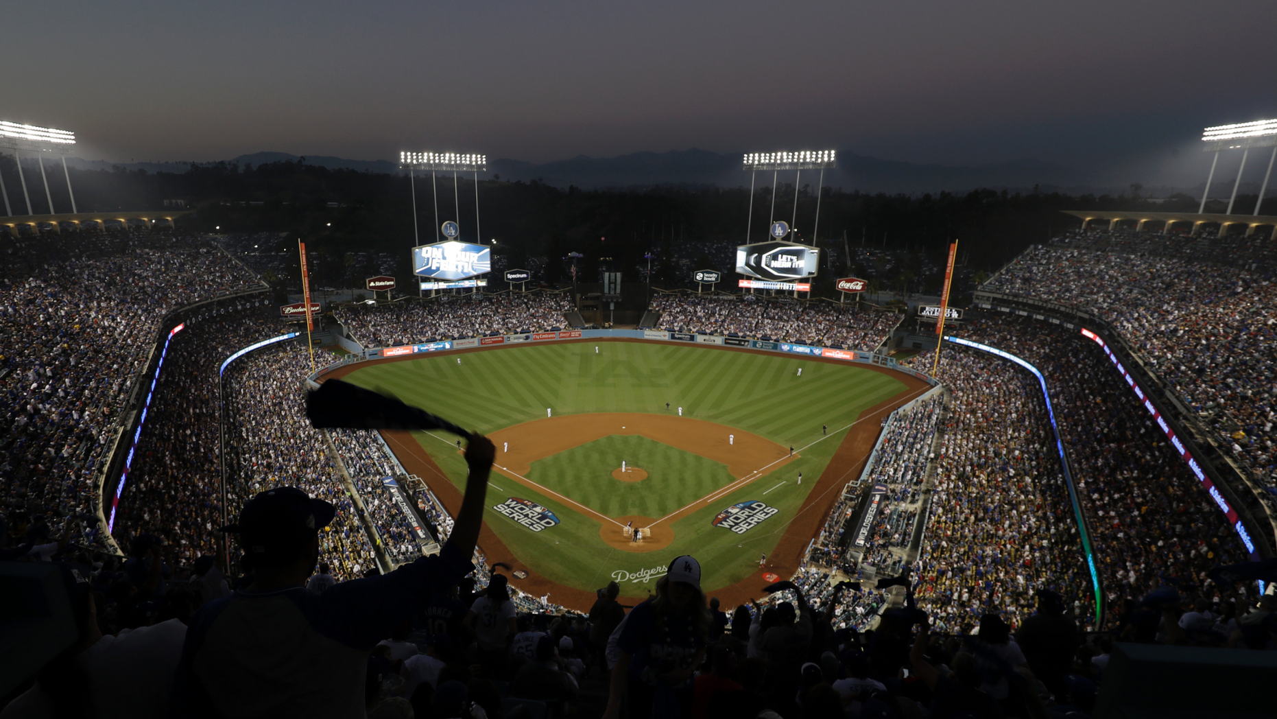 FILE - In this Oct. 27, 2018, file photo, fans cheer from the top of Dodger Stadium during Game 4 of the World Series baseball game between the Boston Red Sox and Los Angeles Dodgers in Los Angeles. Los Angeles police say a 47-year-old man was hospitalized after an argument turned violent outside Dodger Stadium. Police say the man was punched once by another man and fell to the ground in a parking lot following the six-hour game Friday night against the Arizona Diamondbacks. (AP Photo/Elise Amendola, File)