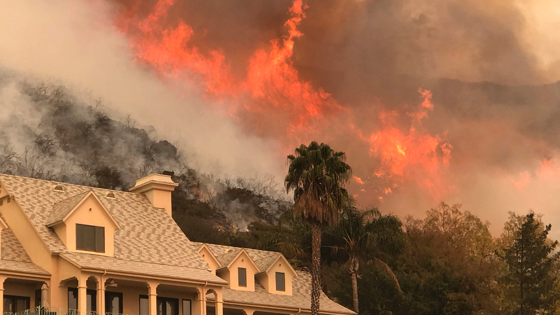 FILE - In this Thursday, Dec. 14, 2017, file photo provided by the Santa Barbara County Fire Department, shows flames from a back firing operation underway rise behind a home off Ladera Ln near Bella Vista Drive in Santa Barbara, Calif. An investigation has determined that one of the largest and most destructive fires in California history was sparked by power lines coming into contact during high winds. The Ventura County Fire Department says Wednesday that the contact ignited dry brush on December 4, 2017 and eventually blackened more than 440 square miles (1,139 square kilometers). The Thomas fire destroyed more than a thousand structures in Ventura and Santa Barbara counties and resulted in the deaths of two people. (Mike Eliason/Santa Barbara County Fire Department via AP,File)