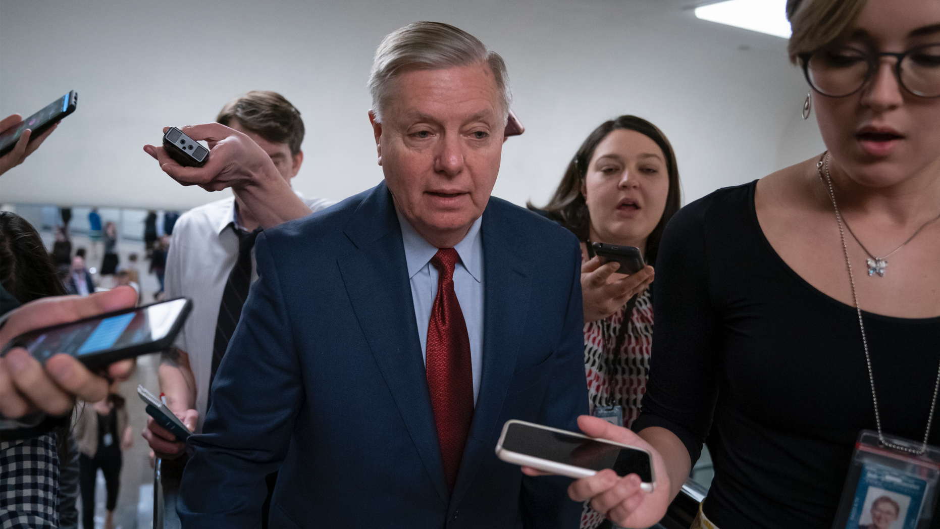 IN this March 13, 2019, photo, reporters pose questions to Sen. Lindsey Graham, R-S.C., at the Capitol in Washington, Wednesday, March 13, 2019. The Republican-led Senate is set to deal President Donald Trump a rebuke on his declaration of a national emergency at the Mexican border, with the only remaining question how many GOP senators will join Democrats in defying him. (AP Photo/J. Scott Applewhite)