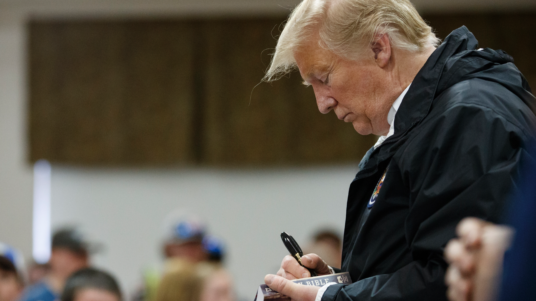 President Donald Trump signs a Bible as he greets people at Providence Baptist Church in Smiths Station, Ala., Friday, March 8, 2019, during a tour of areas where tornados killed 23 people in Lee County, Ala. (AP Photo/Carolyn Kaster)