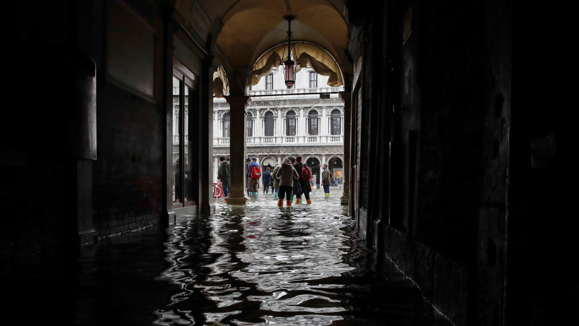 FILE - In this Thursday, Nov. 1, 2018 file photo, tourists walk in the flooded St. Mark's Square in Venice, Italy, as rainstorms and strong winds hit the area. On Thursday, March 28, 2019, the United Nations’ weather agency says extreme weather in 2018 hit 62 million people worldwide last year and created 2 million refugees as man-made climate change worsened. (AP Photo/Luca Bruno)