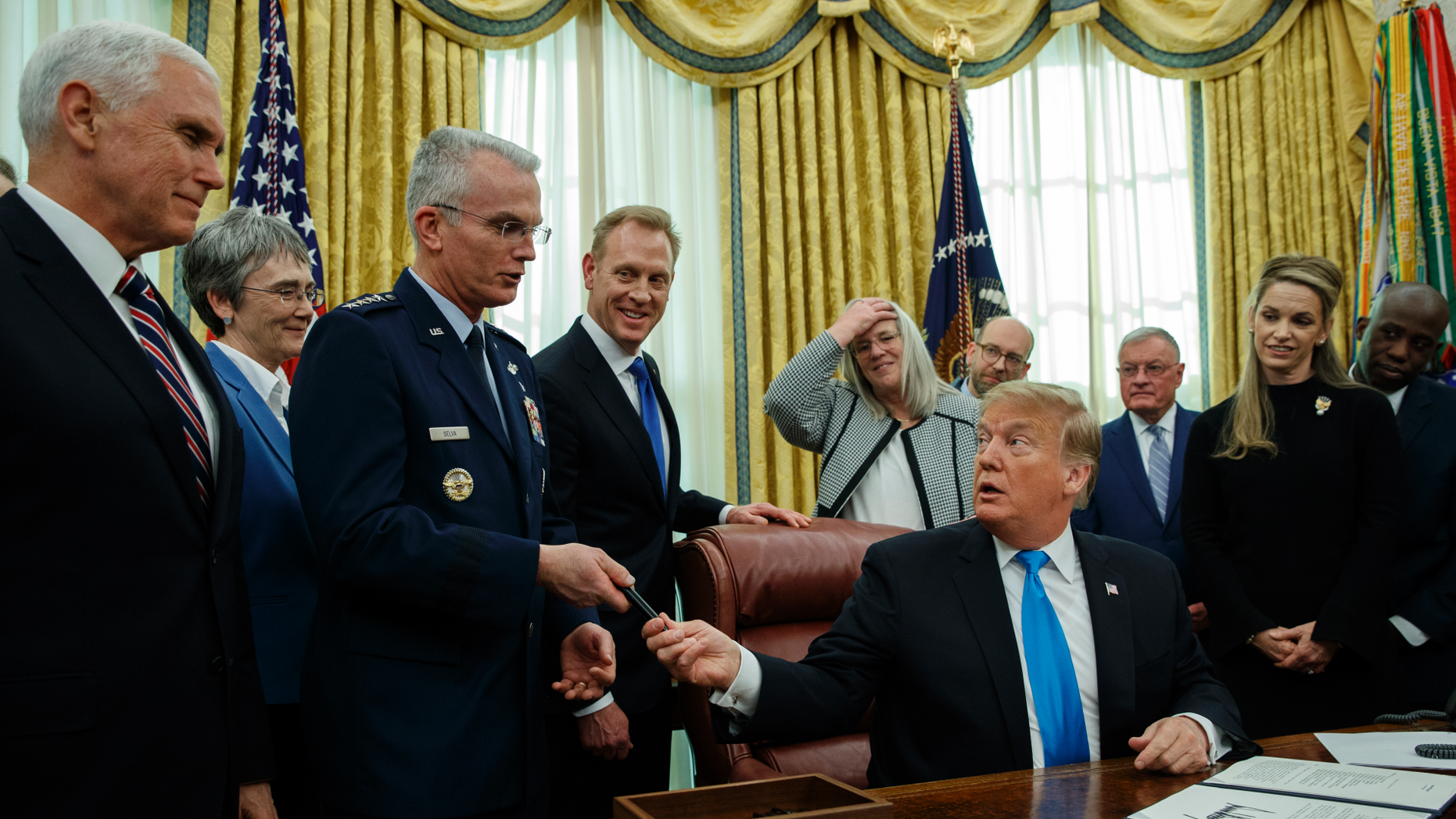 President Donald Trump hands General Paul Selva a pen after signing 