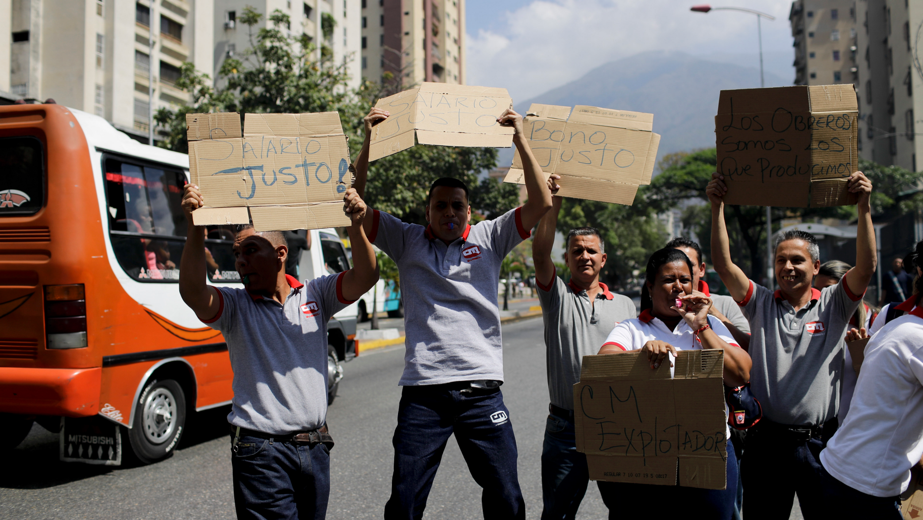 Supermarket employees holds up a pieces of cardboard with a handwritten messages demanding better salaries, in Caracas, Venezuela, Wednesday, March 20, 2019. (AP Photo/Natacha Pisarenko)