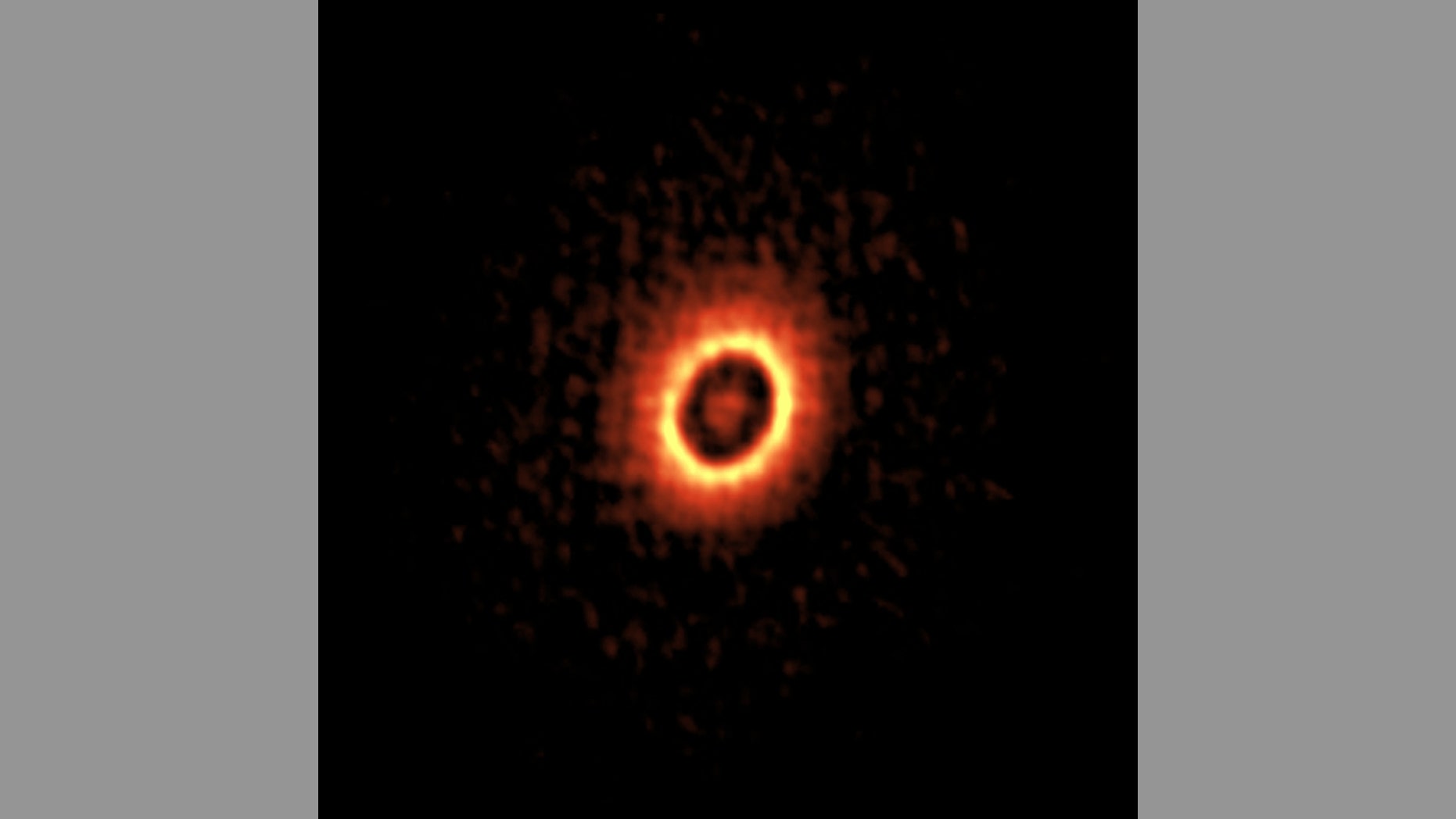 ALMA image of the dusty disk around the young star DM Tau. Two concentric rings, where planets may be forming, are visible.