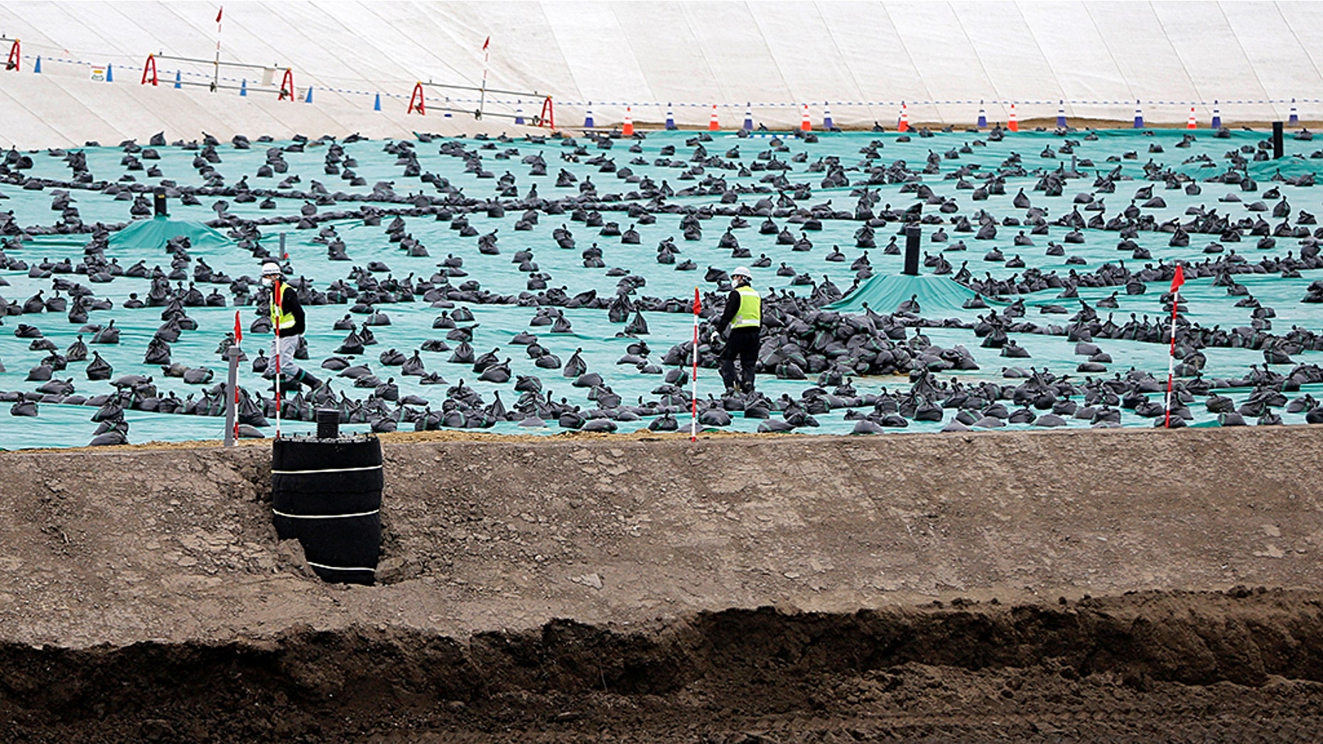 Workers are seen in February at a soil storage facility for decontamination work, near Tokyo Electric Power Co's tsunami-crippled Fukushima Daiichi nuclear power plant, in Okuma Town, Fukushima prefecture.