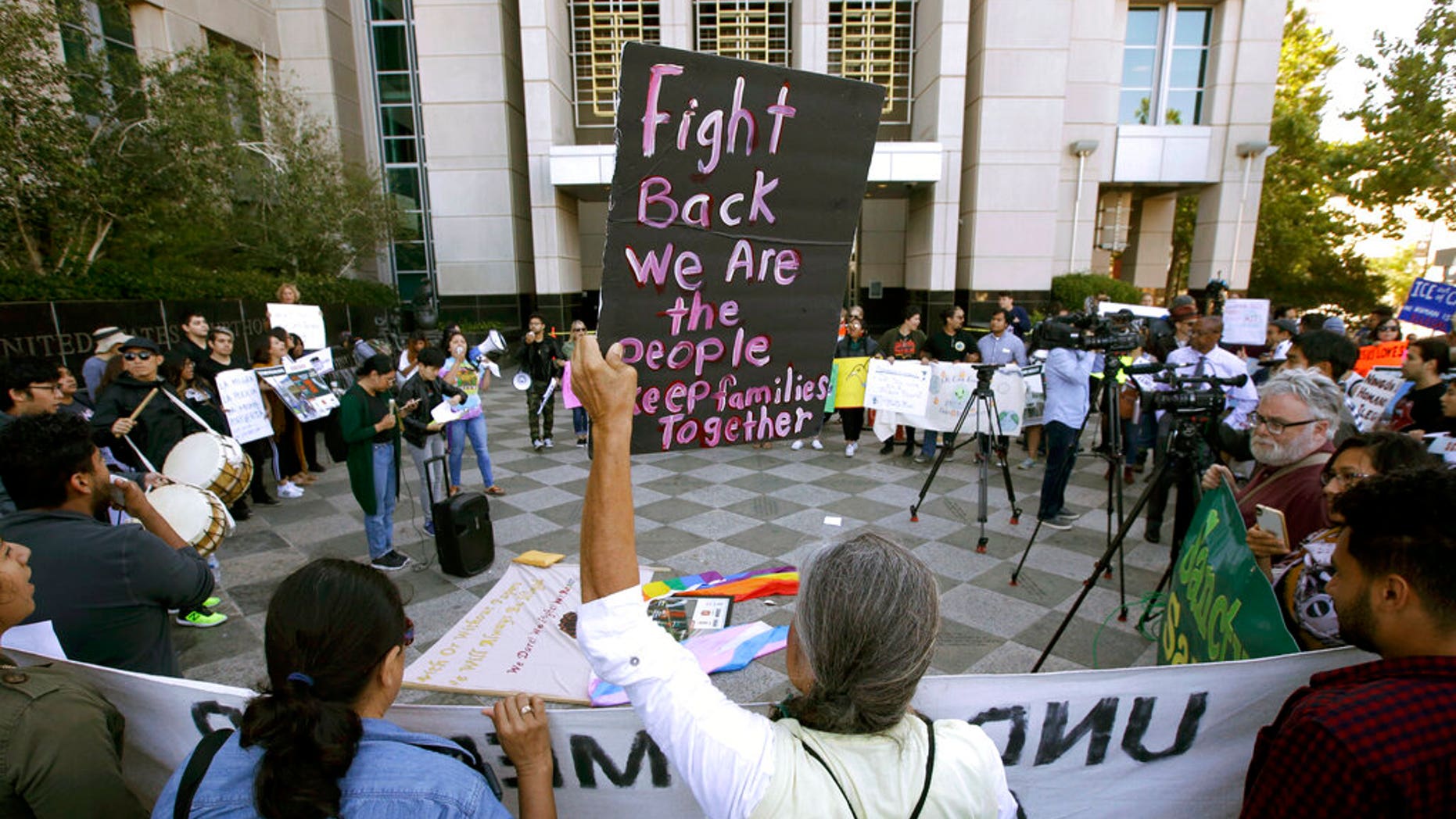 FILE - In this June 20, 2018, file photo, protesters demonstrate outside the federal courthouse in Sacramento, Calif., where a judge heard arguments over the U.S. Justice Department's request to block three California laws that extend protections to people in the country illegally. The Justice Department told The Associated Press at the end of February 2019 that 28 jurisdictions, including Sacramento, that were targeted in 2017 over what it considered "sanctuary" policies have been cleared for law enforcement grant funding. (AP Photo/Rich Pedroncelli, File)