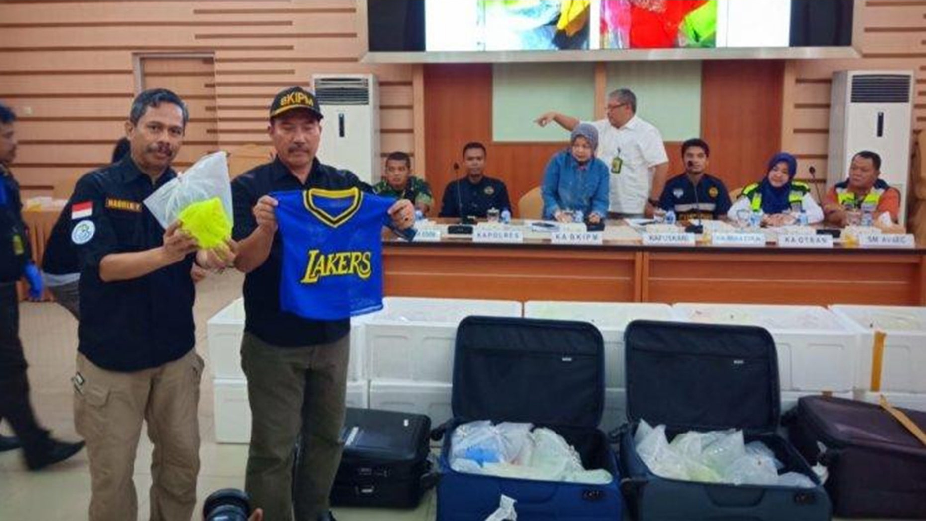 Officers from the Fish Quarantine and Fishery Quality Control Agency hold up the bags and clothes used to smuggle in thousands of lobster seeds.