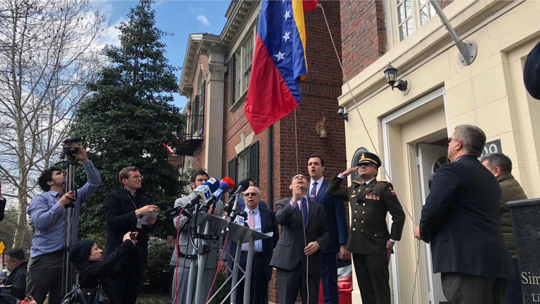 Juan Guaido's ambassador to the U.S., Carlos Vecchio, raising a Venezuelan flag outside a building belonging to Venezuela's defense ministry Monday in Washington, D.C.