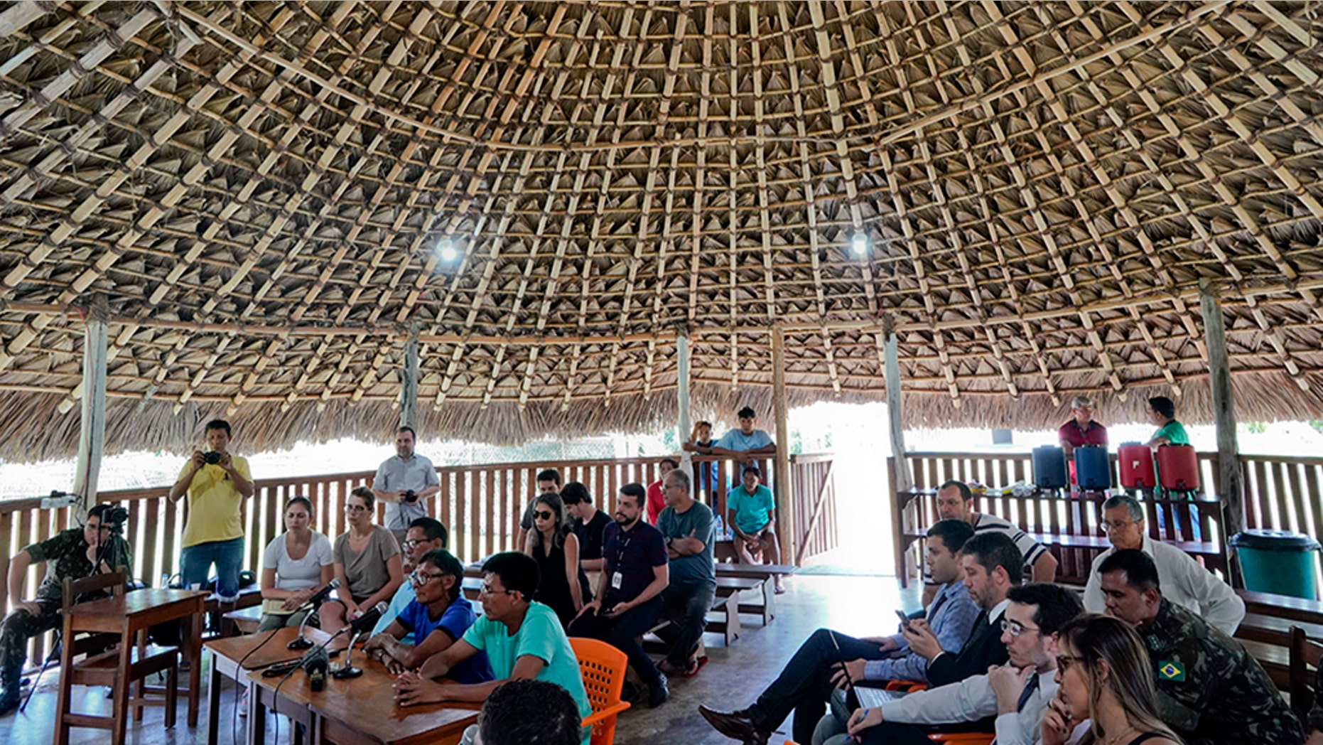 Temehe Tomas Waimiri, sitting center left and wearing blue shirt and glasses, gives testimony about alleged crimes committed by the Brazilian dictatorship in the 1970s, during a hearing inside a traditional "maloca" indigenous hut, at the Waimiri-Atroari reserve in Amazon state, Wednesday, Feb. 27, 2019. (AP Photo/Victor R. Caivano)