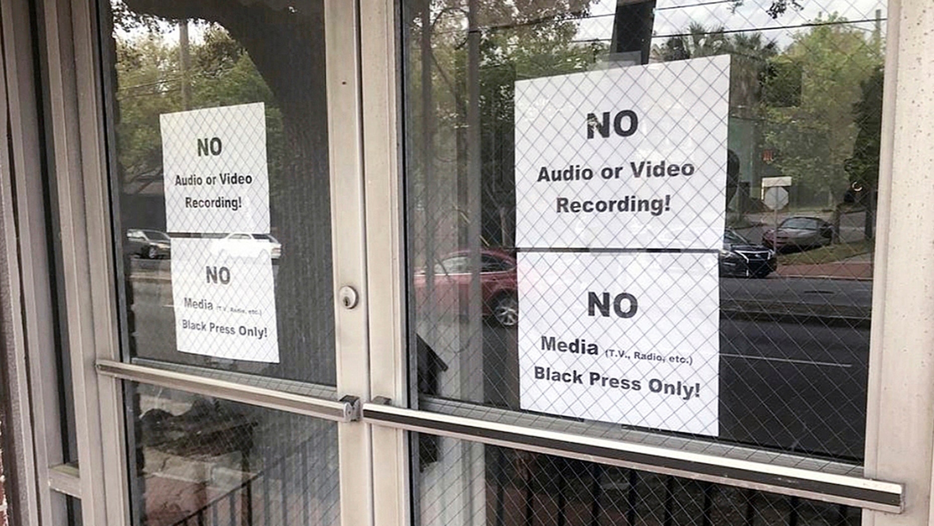 In this photo from Wednesday, March 27, 2019, signs posted on the doors of the Baptist Church of Bolten Street are visible during a coordinated meeting to garner support from a black candidate in the Savannah Town Hall Race in Savannah, Georgia. The organizers of a meeting to discuss an upcoming mayoral race in Georgia banned reporters from attending, unless they are African-Americans. (Eric Curl / Savannah Morning News via AP)