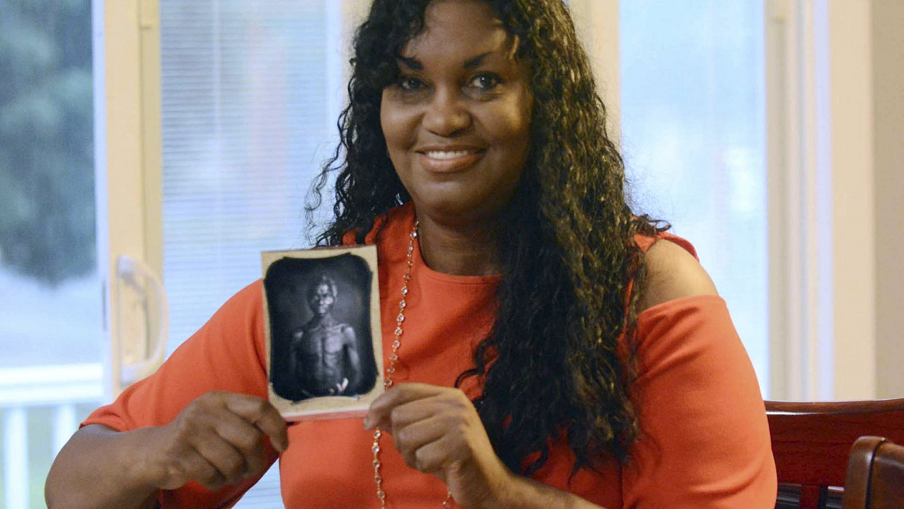 In this July 17, 2018, photo, Tamara Lanier holds an 1850 photograph of Renty, a South Carolina slave who Lanier said is her family's patriarch, at her home in Norwich, Conn. The portrait was commissioned by Harvard biologist Louis Agassiz, whose ideas were used to support the enslavement of Africans in the United States. Lanier filed a lawsuit on Wednesday, March 20, 2019 in Massachusetts state court, demanding that Harvard turn over the photo and pay damages.