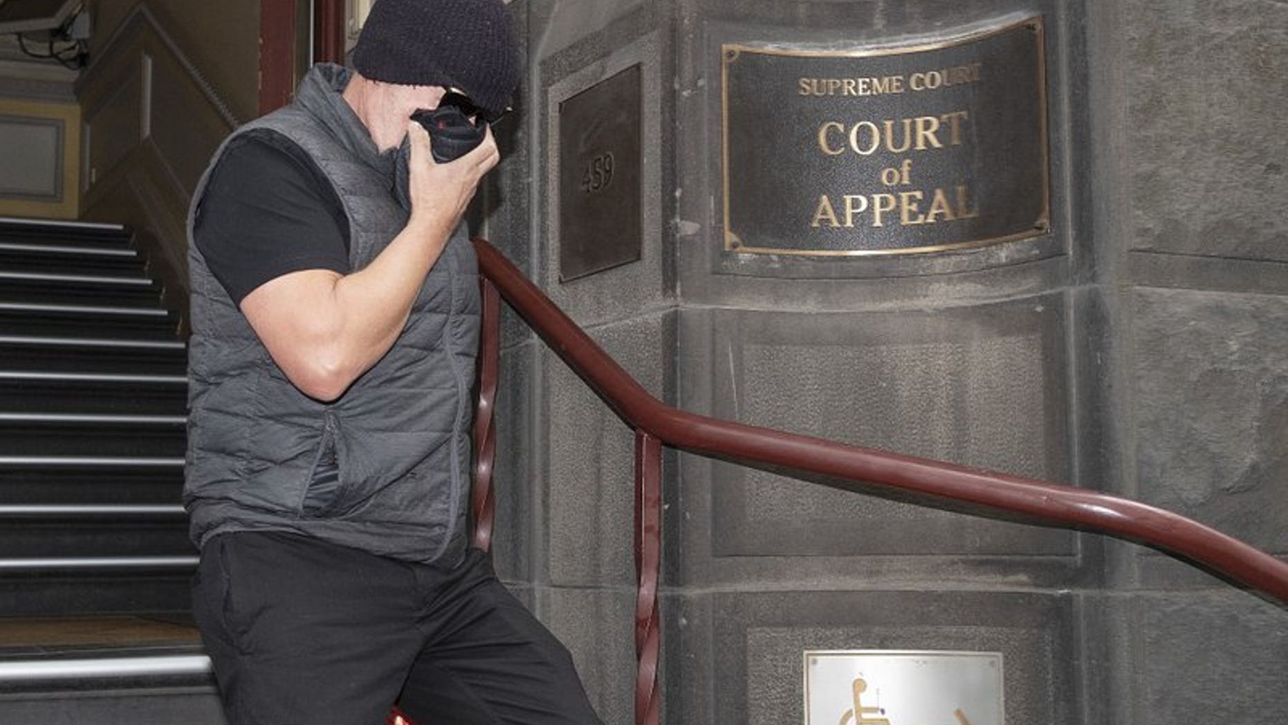 Workplace bullying claimant David Hingst covers his face as he leaves the Court of Appeal in Melbourne, Australia Friday, March 29, 2019. The Australian appeals court on Friday dismissed a bullying case brought by the engineer Hingst who accused his former supervisor of repeatedly breaking wind toward him.