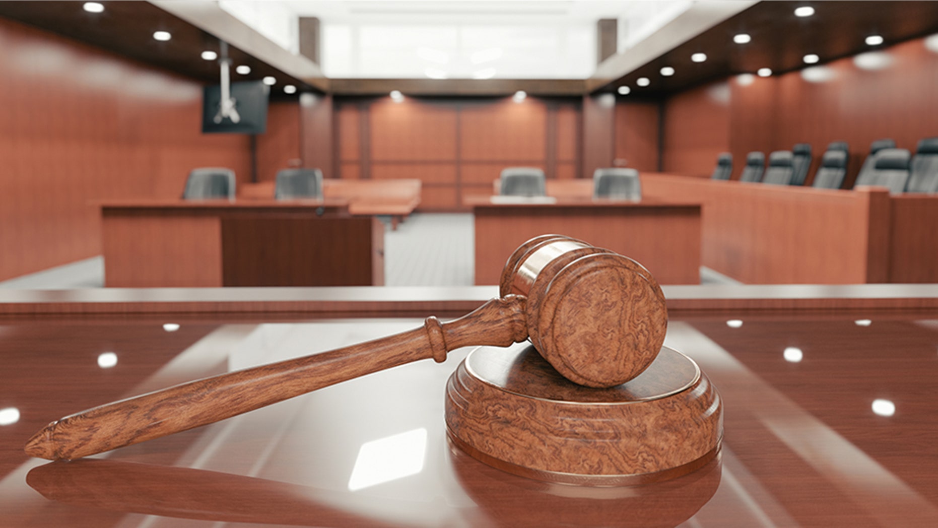 Interior of an empty courtroom with gavel and sounding block on the desk.