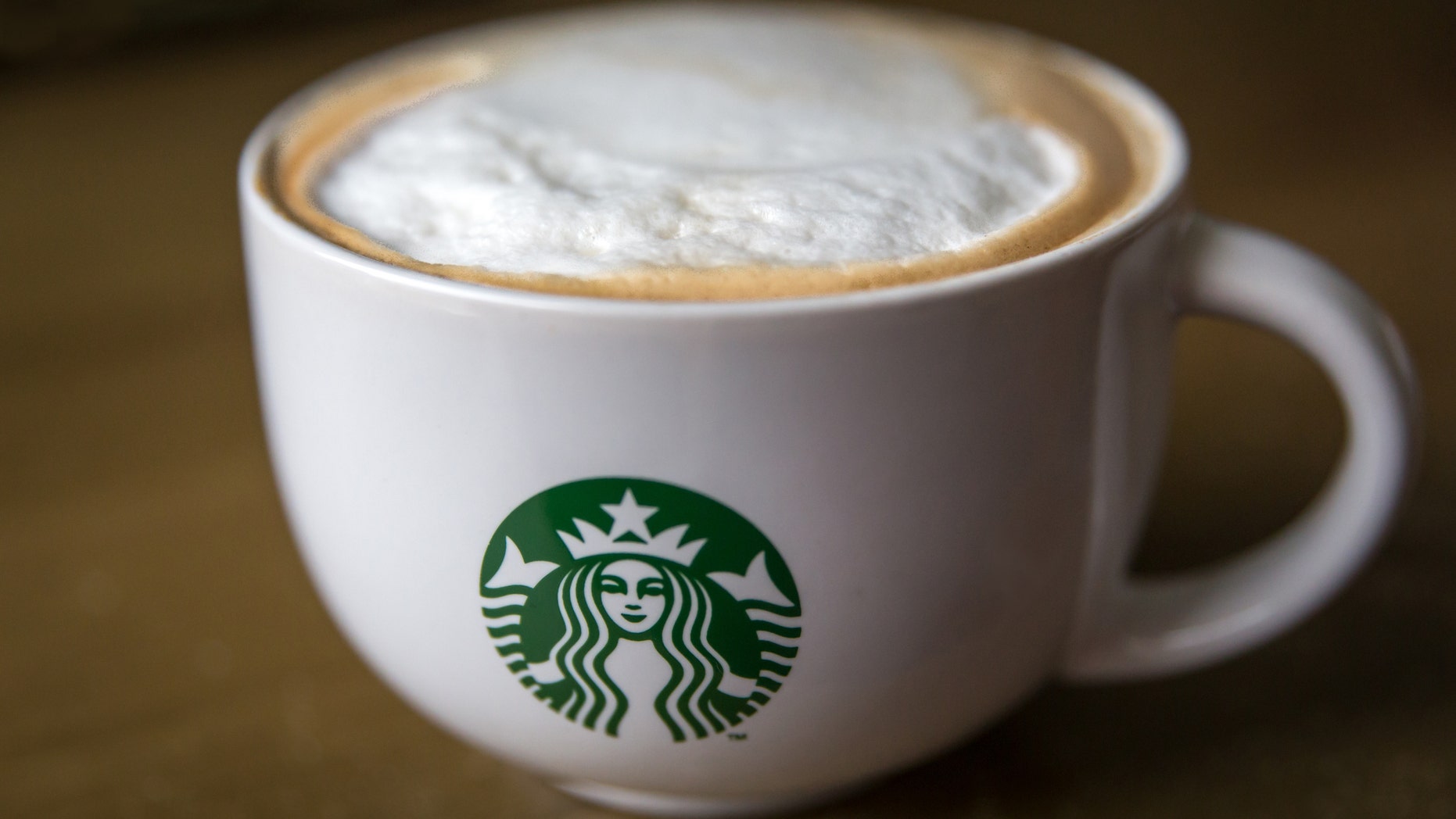 Close up of a Starbucks branded Cappucino Mug on a brown table.