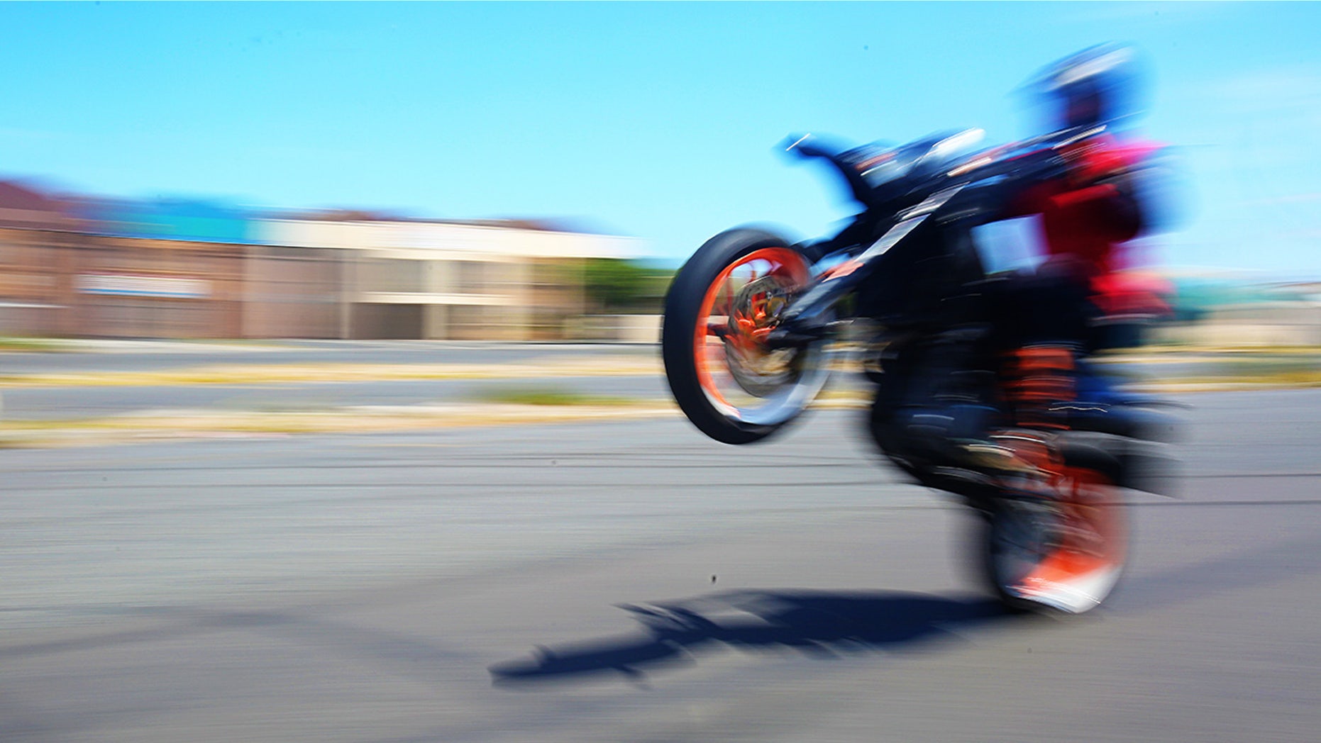 Biker pops a wheelie on asphalt street with blurred motion
