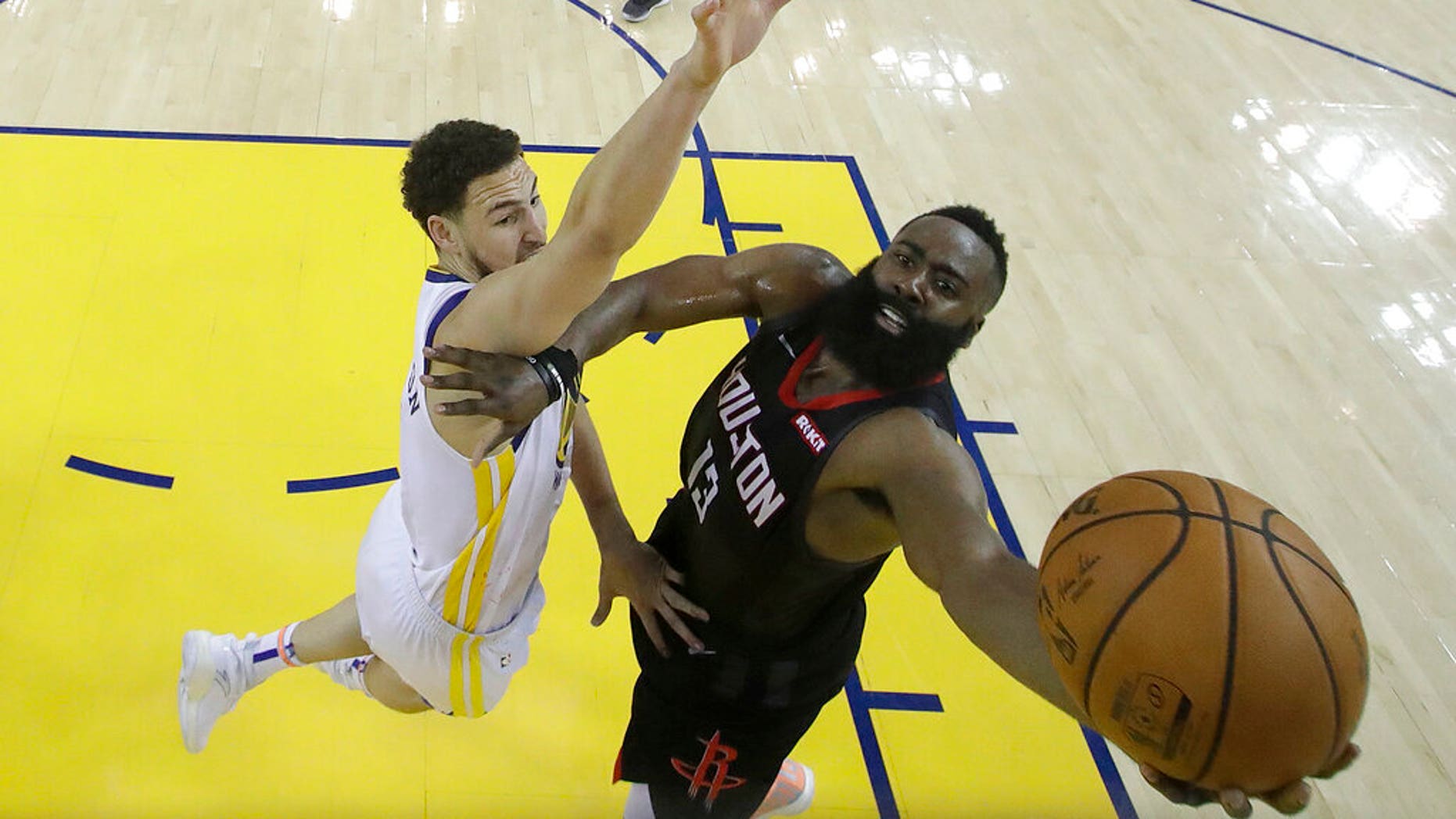 Houston Rockets guard James Harden, right, shoots against Golden State Warriors guard Klay Thompson during the second half of Game 1 of a second-round NBA basketball playoff series in Oakland, Calif.