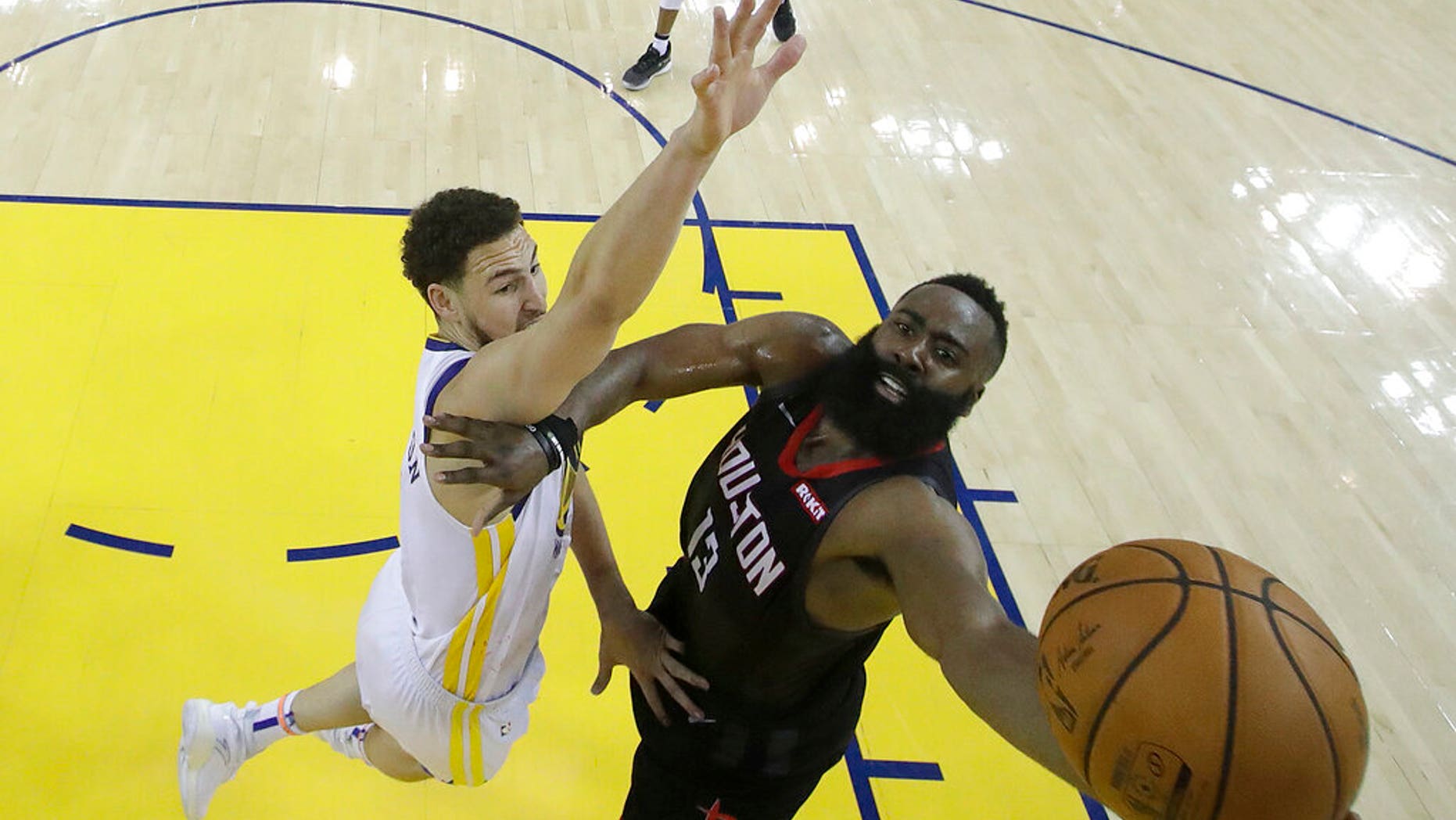 Houston Rockets guard James Harden, right, shoots against Golden State Warriors guard Klay Thompson during the second half of Game 1 of a second-round NBA basketball playoff series in Oakland, Calif.