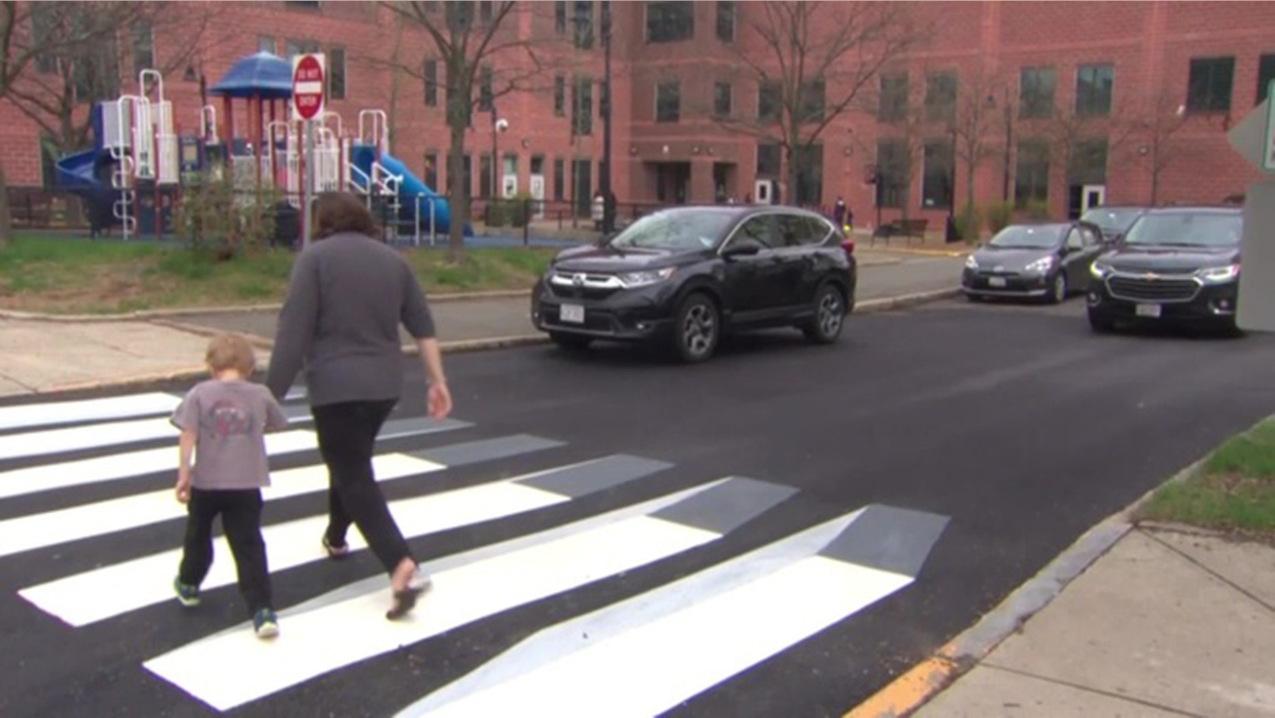 A pedestrian walks across the newly designed 3D crosswalk. The walkway was designed by a pair of fourth graders in Massachusetts.